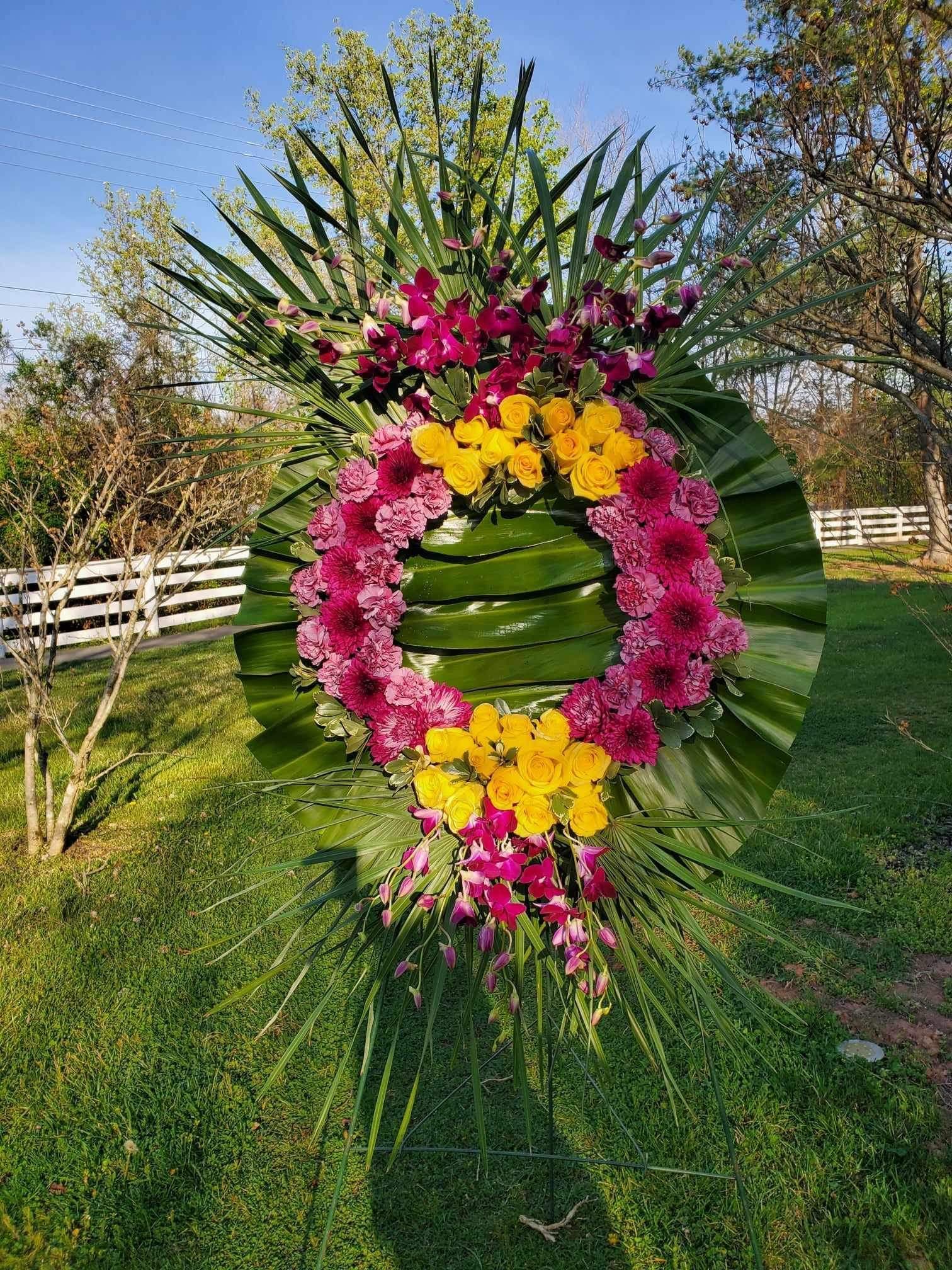 Large floral wreath with pink, yellow, and purple flowers on palm fronds