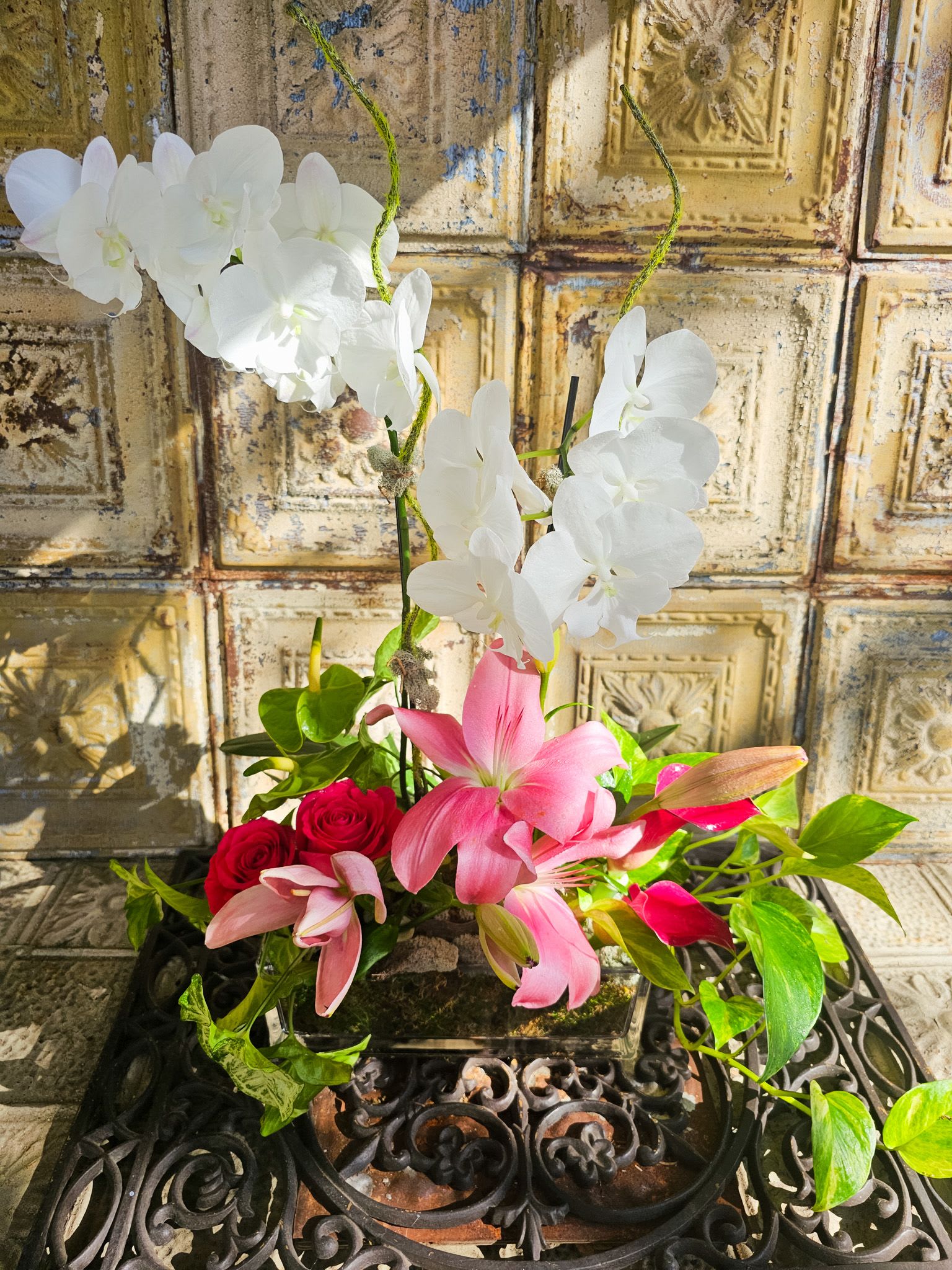 Pink lilies, red roses, and white orchids in a low arrangement