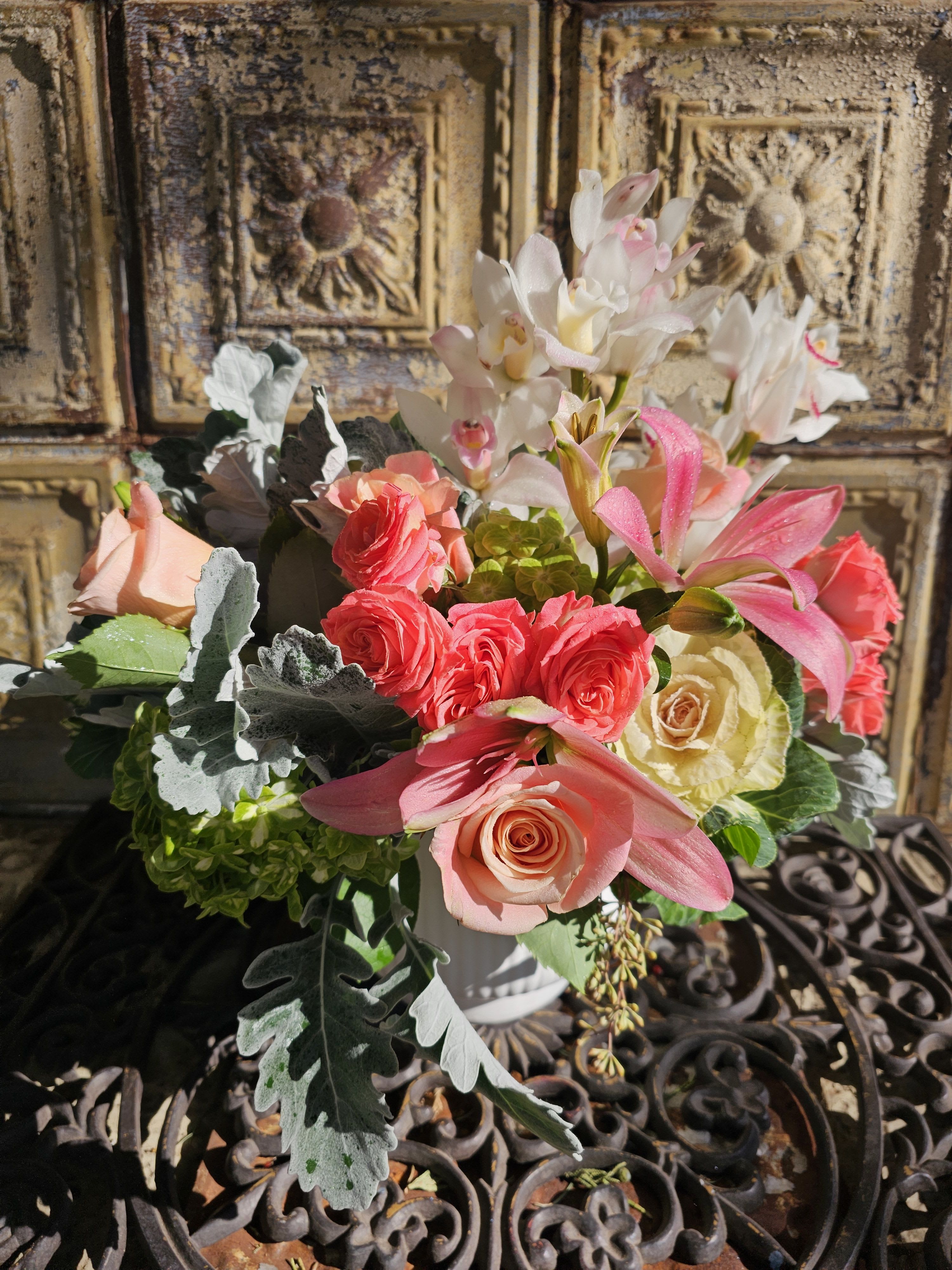 Bouquet of pink and cream roses with white orchids in a white vase