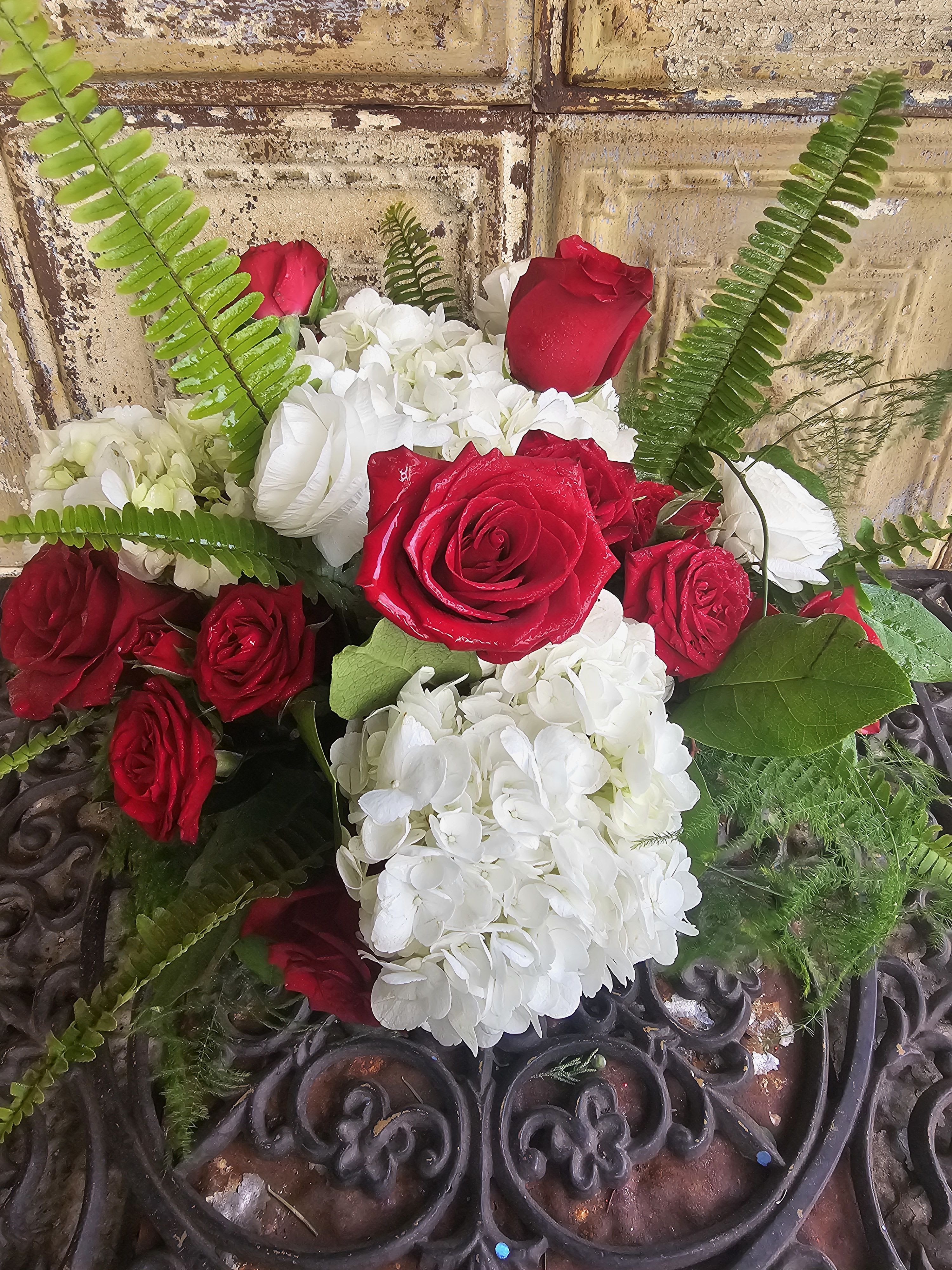 Red roses and white hydrangeas arranged with fern fronds