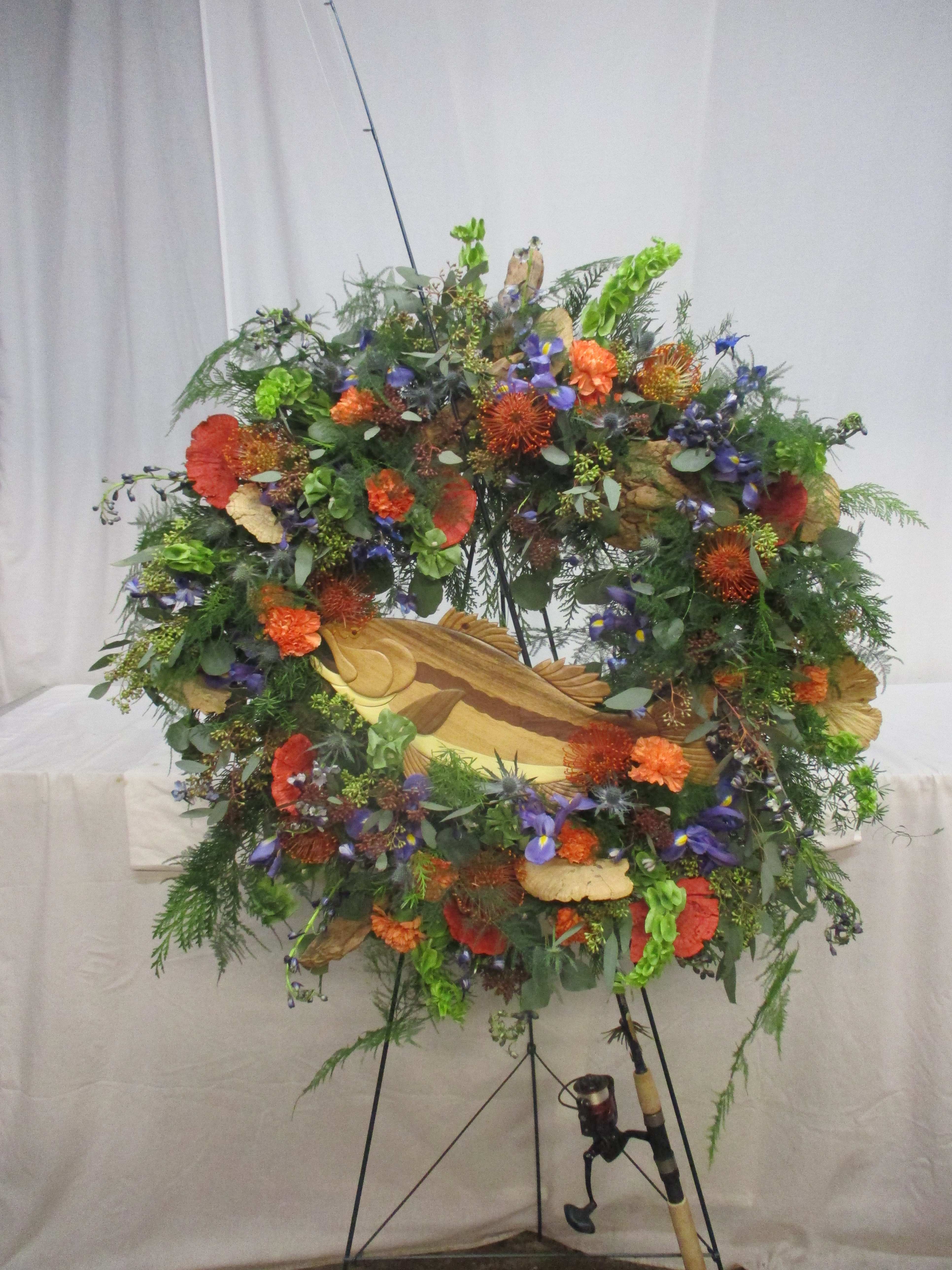 Large floral wreath on a stand with orange, purple, and green blooms