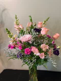 Mixed pink and purple flower arrangement in a clear glass vase