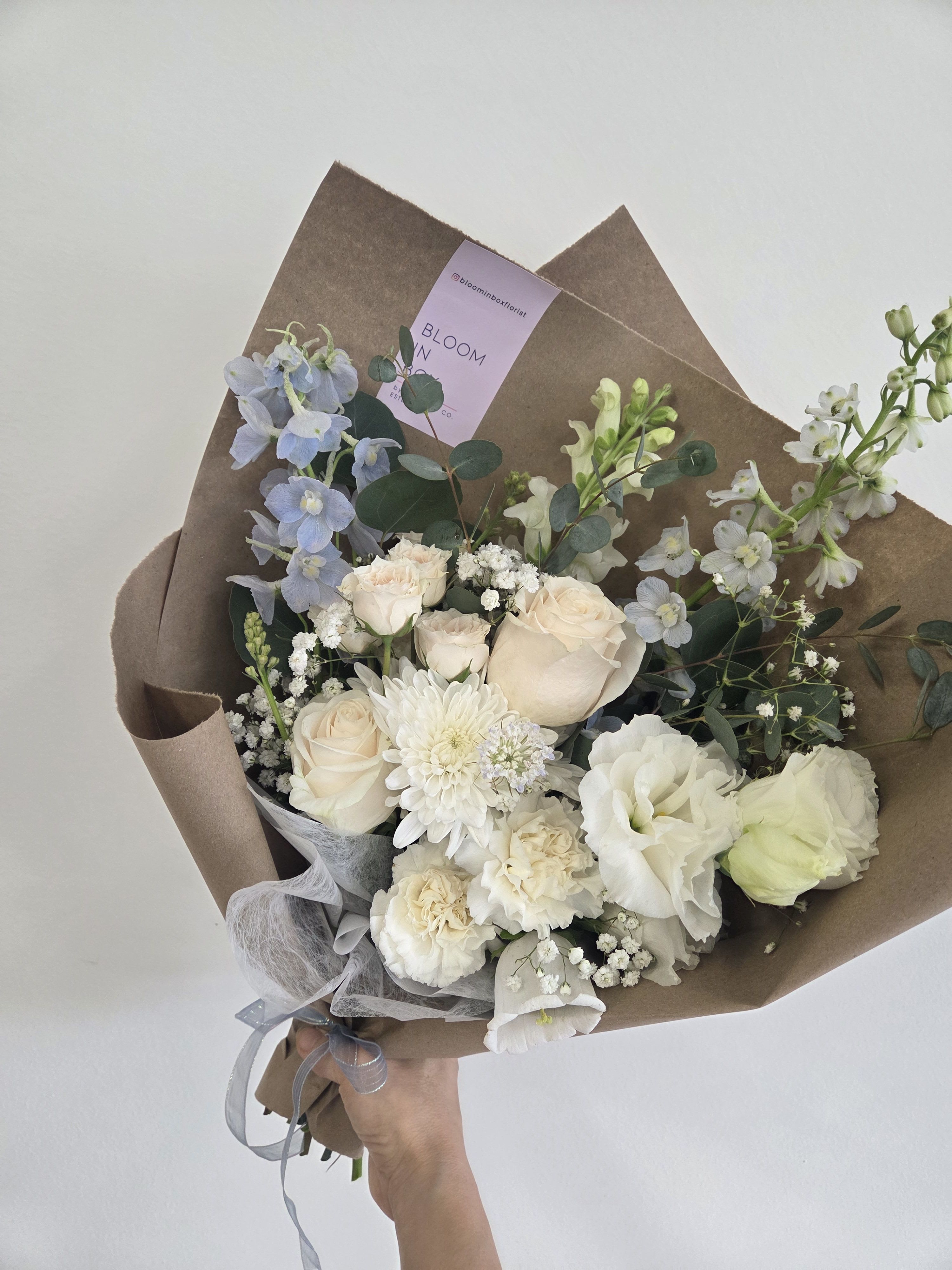 Creamy Sky Hand-tied Bouquet (New!) - Hand-held Bouquet The bouquet shown in the photo is our Standard Size, wrapped in brown kraft paper.  Mon–Fri: 9:30 a.m. – 6:00 p.m. Sat: 9:00 a.m. – 4:00 p.m. Sun: Closed  Delivery Deliveries are typically made between 9:00 a.m. and 3:00 p.m. While we are unable to guarantee specific delivery times, we will always do our best to accommodate your requests. If you prefer a later afternoon delivery, please let us know in advance and we will try to accommodate. If your delivery address requires a gate code, please provide it to ensure smooth delivery.  Pick-Up Please also try to pick up your order at the scheduled time. When pick-ups are delayed during busy time slots, it may affect other customers placing orders for the same time. We appreciate your understanding!  Please Note Your arrangement may vary slightly from the photos depending on seasonal availability and store stock. However, we will match the overall color palette and ensure your flowers are fresh and beautifully designed.  Thank you!