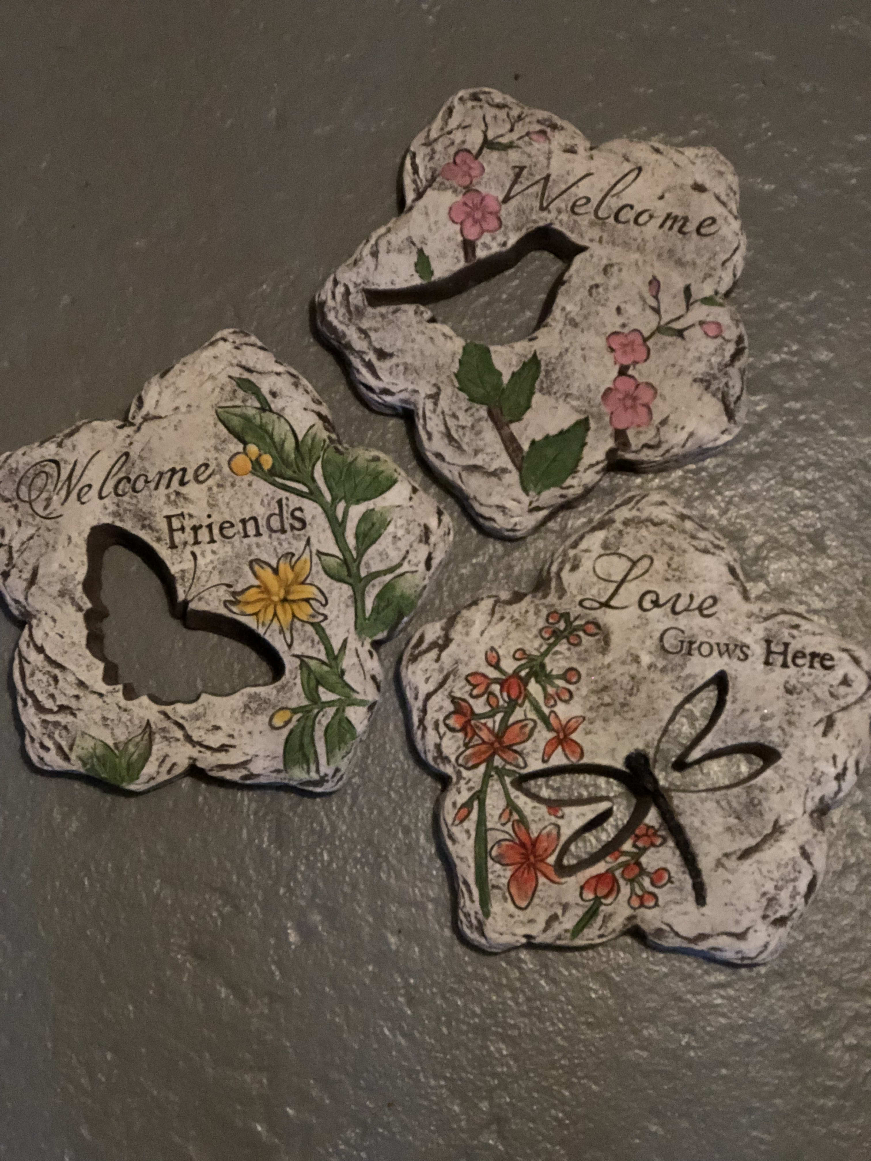 Three decorative stone plaques with floral designs and welcome messages