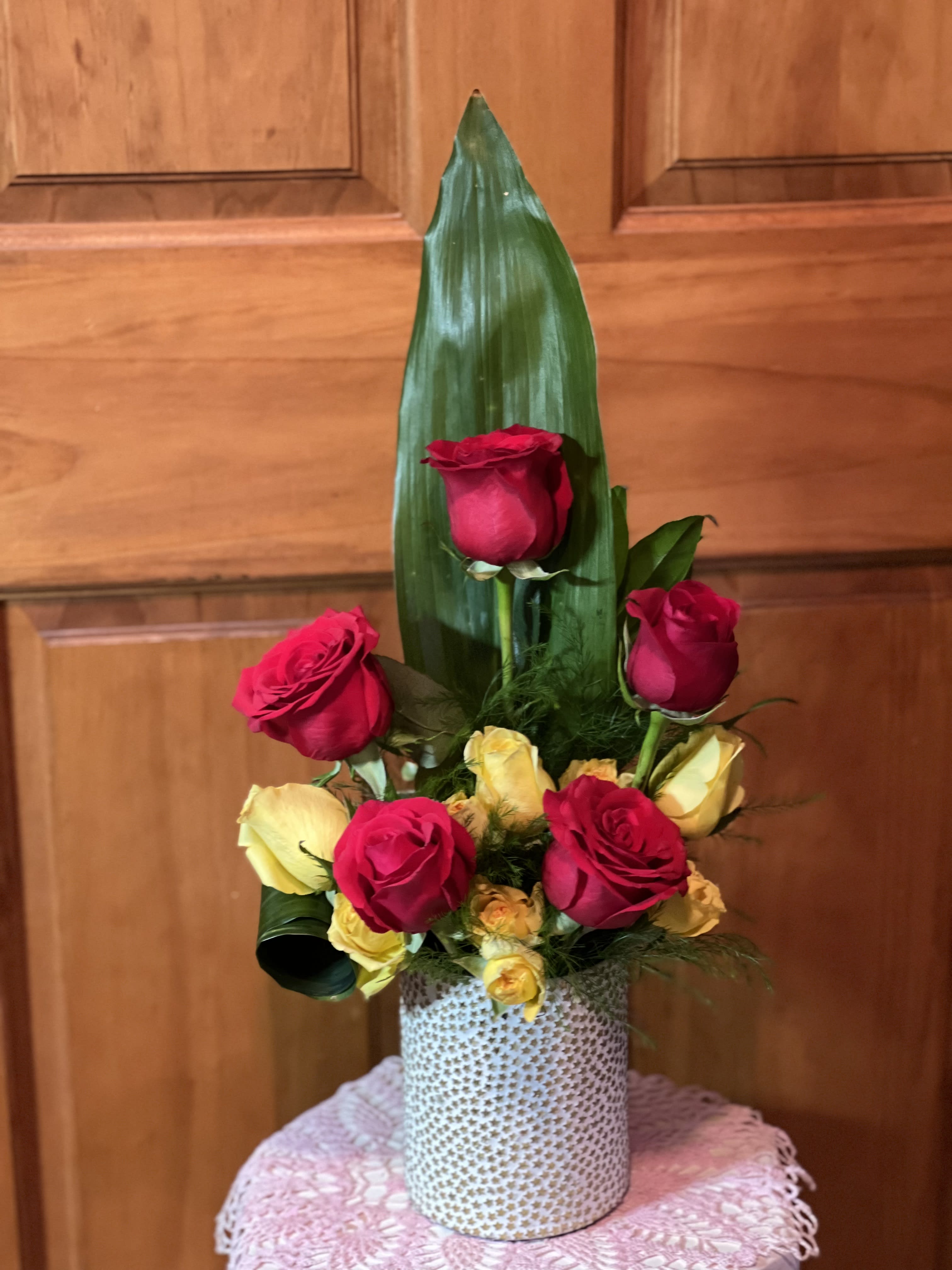 Tall arrangement of red and yellow roses in a patterned vase