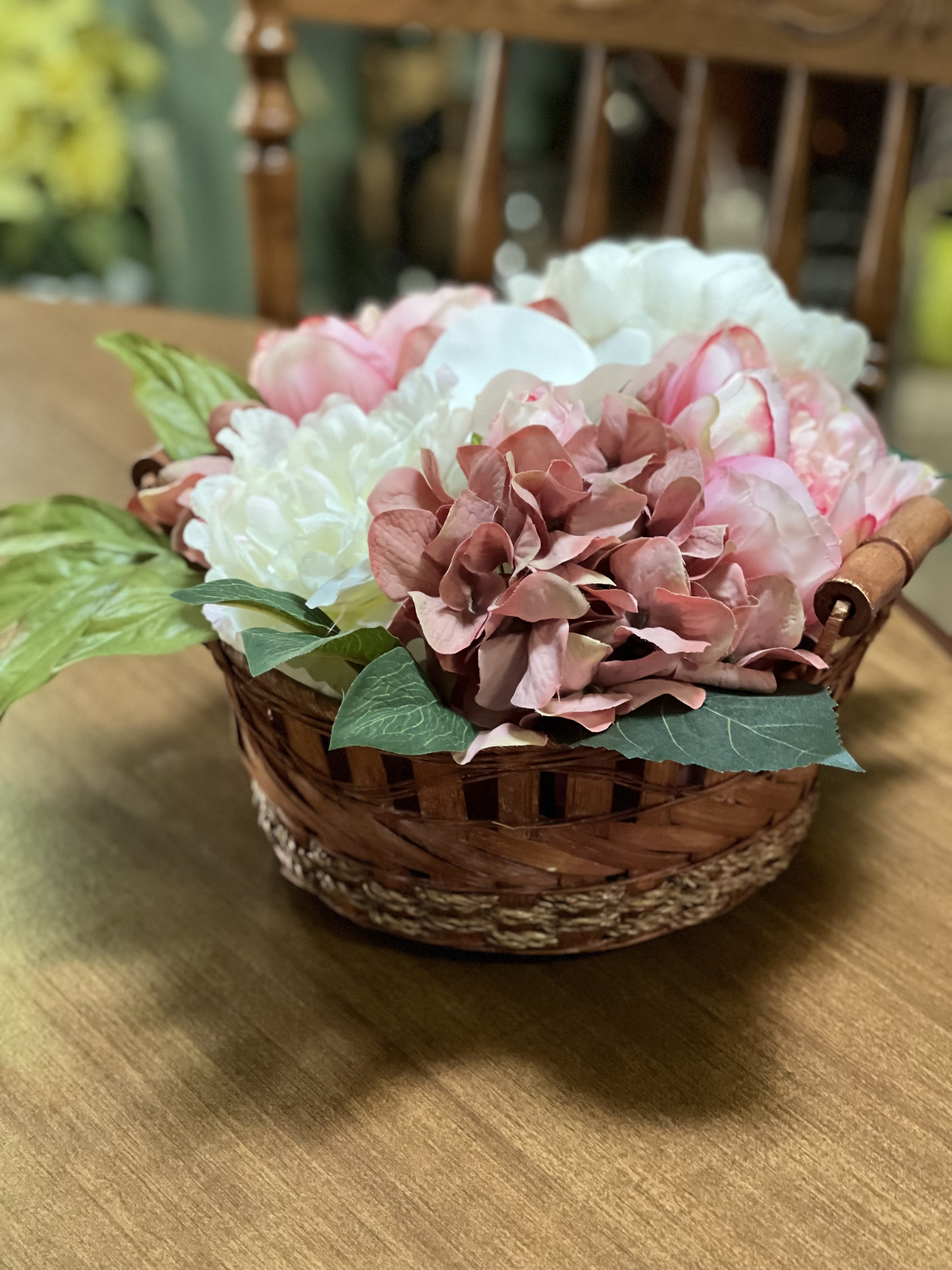 Basket of pink and white flowers on a wooden table