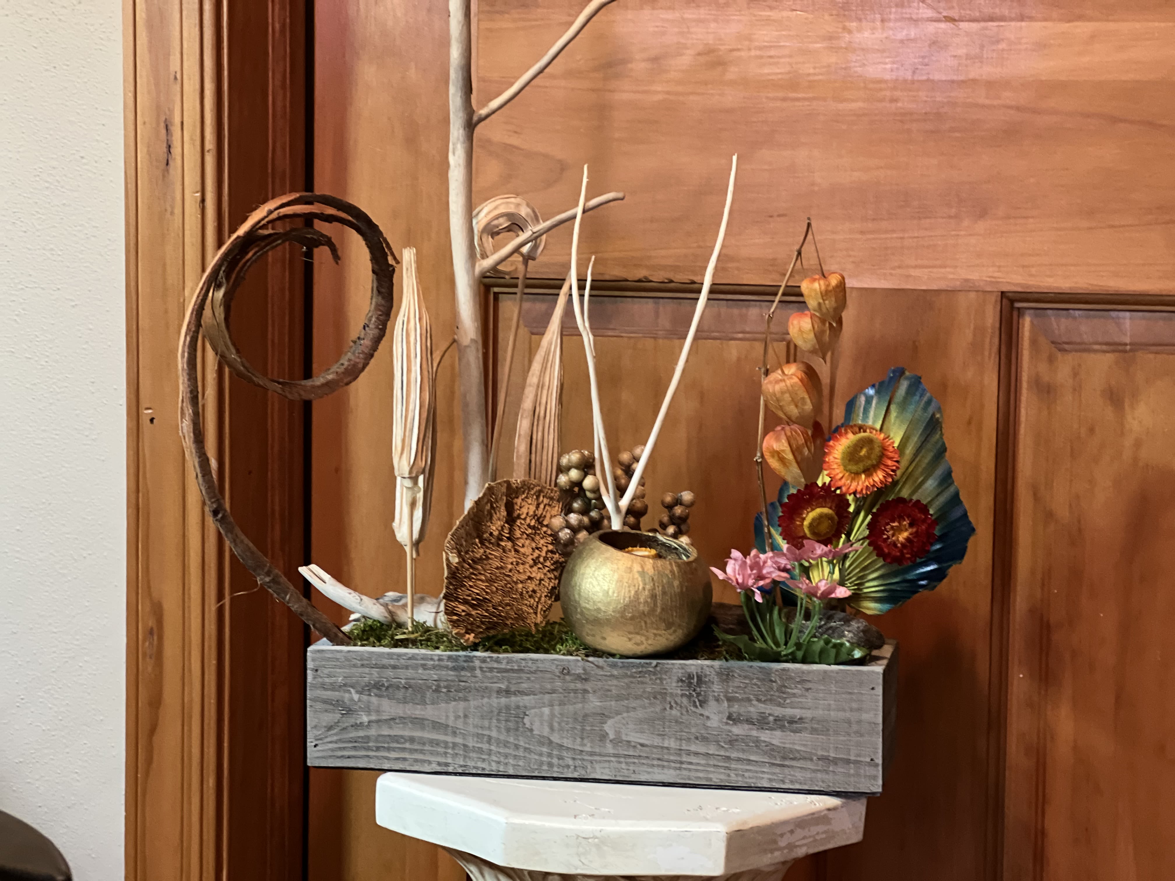 Decorative floral arrangement in a gray wooden box with dried accents and colorful blooms