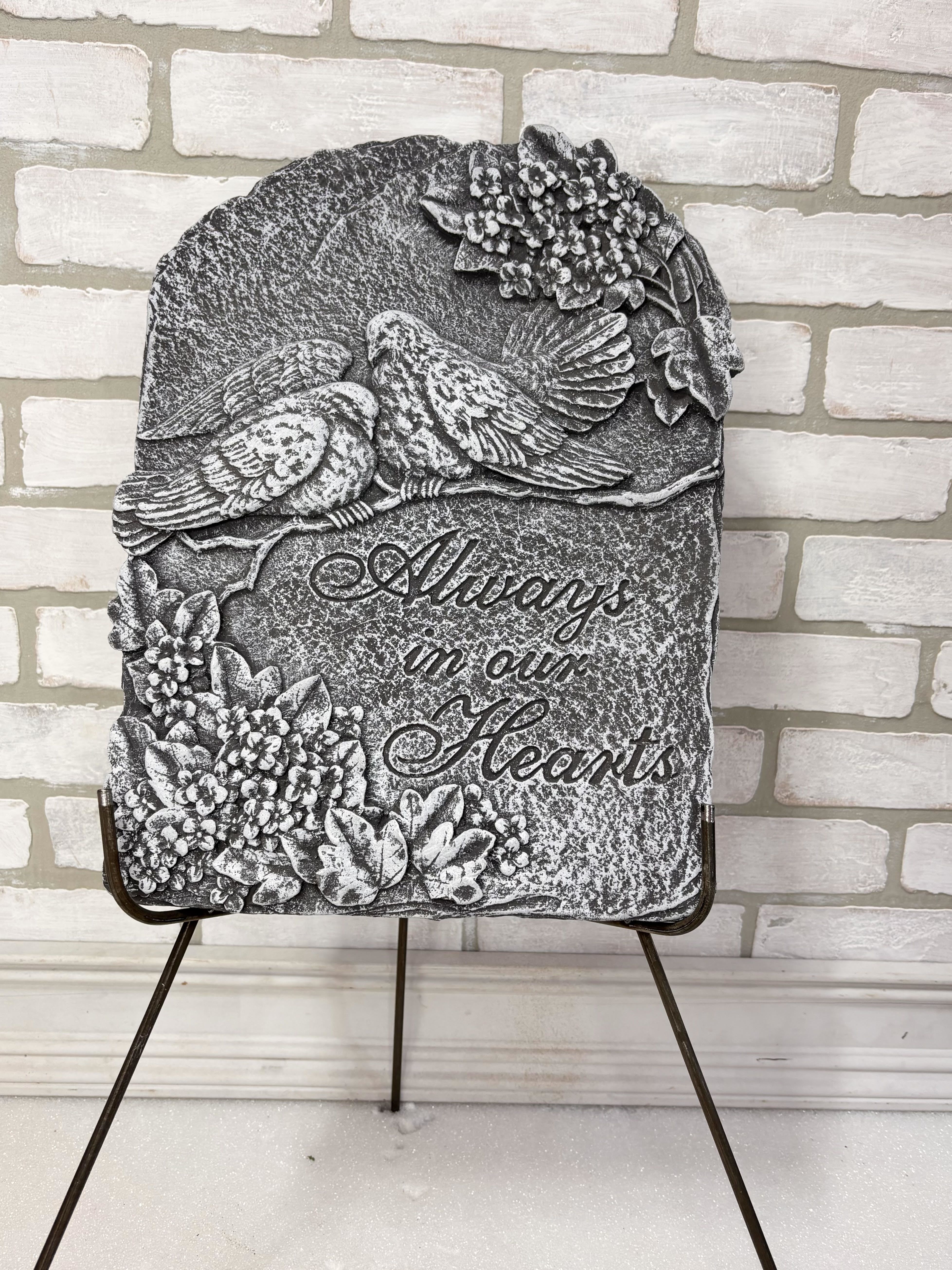 Stone memorial plaque with two birds and floral relief, reading "Always in our Hearts"