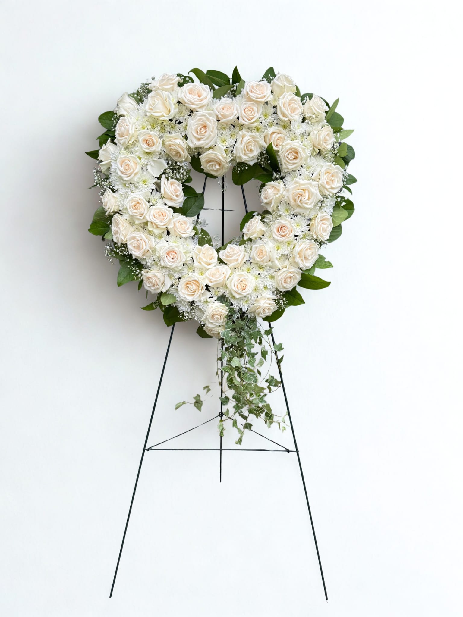 Love in our HEARTS - An all white tribute, this heart shaped easel shows your everlasting love. Featuring a variety of white flowers and greenery, this heart with a trail of ivy compliments the beauty of life. 
