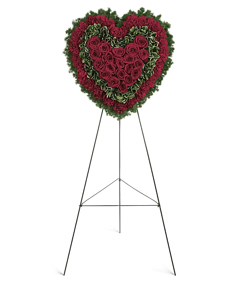Heart-shaped floral wreath of red roses and carnations on a stand