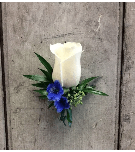 White rose boutonniere with blue flowers and greenery