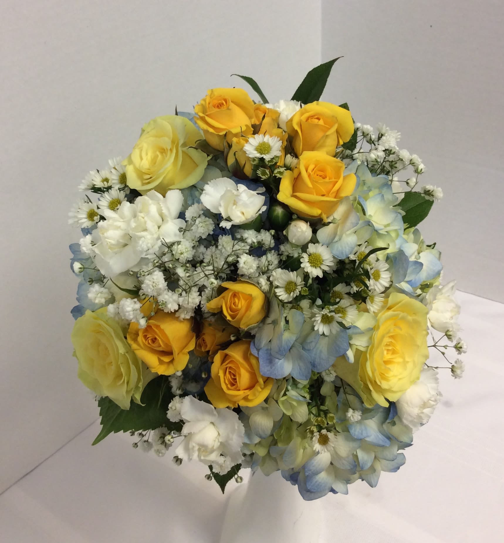 Bouquet of yellow roses, blue hydrangeas, and white filler flowers