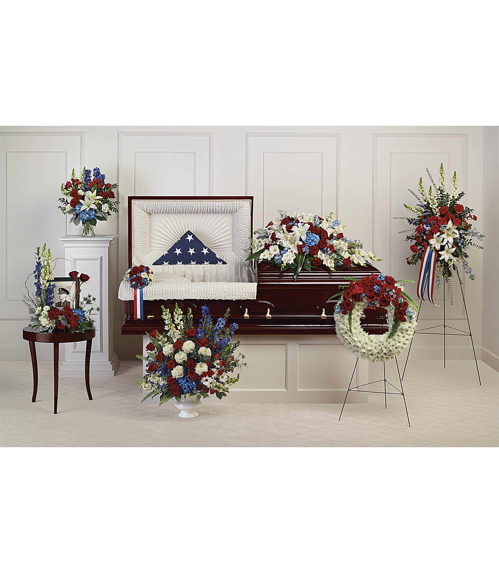 Casket surrounded by red, white, and blue funeral flower arrangements