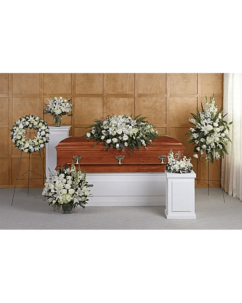 White funeral casket surrounded by white floral arrangements