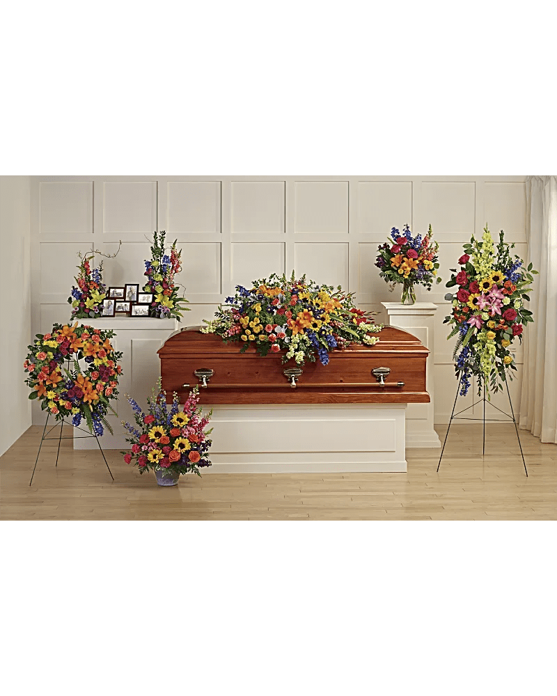 Casket surrounded by colorful funeral flower arrangements in a chapel setting