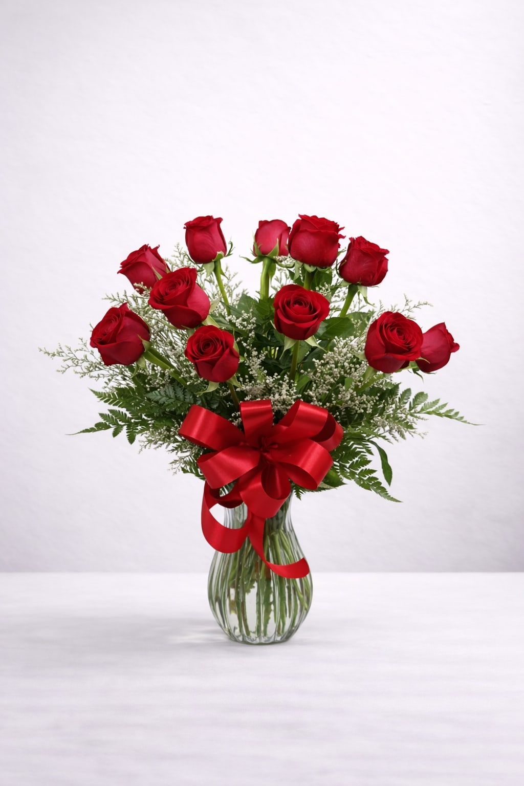 Red roses in a glass vase with a red ribbon bow