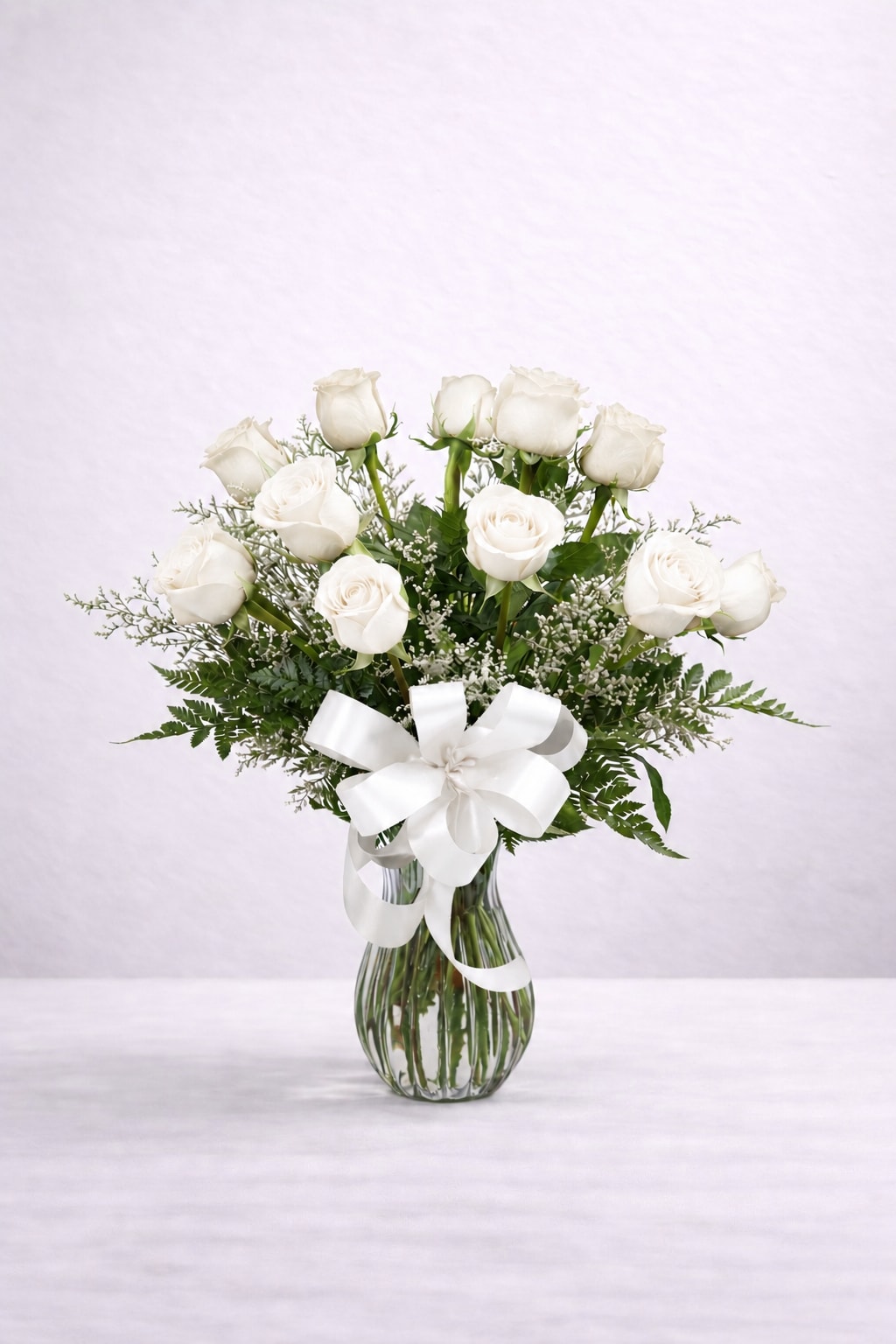 White Roses - Meaning: Purity, reverence, sympathy, and new beginnings  White roses are timeless and versatile, often chosen for moments that call for grace, remembrance, or refined simplicity. Accent flowers and greenery may vary depending on availability.  Standard: 12 roses Deluxe: 18 roses Premium: 24 roses  Looking for a different number of roses? Please call our store at (215) 220-1000 and we’ll be happy to create a custom arrangement for you.