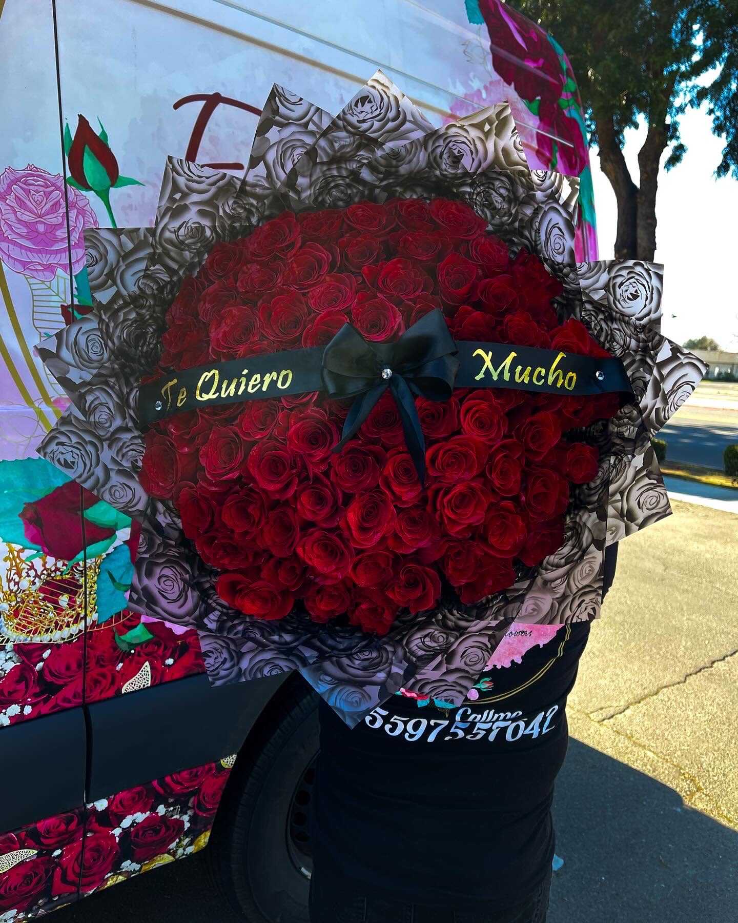 Large bouquet of red roses with a black ribbon and Spanish text