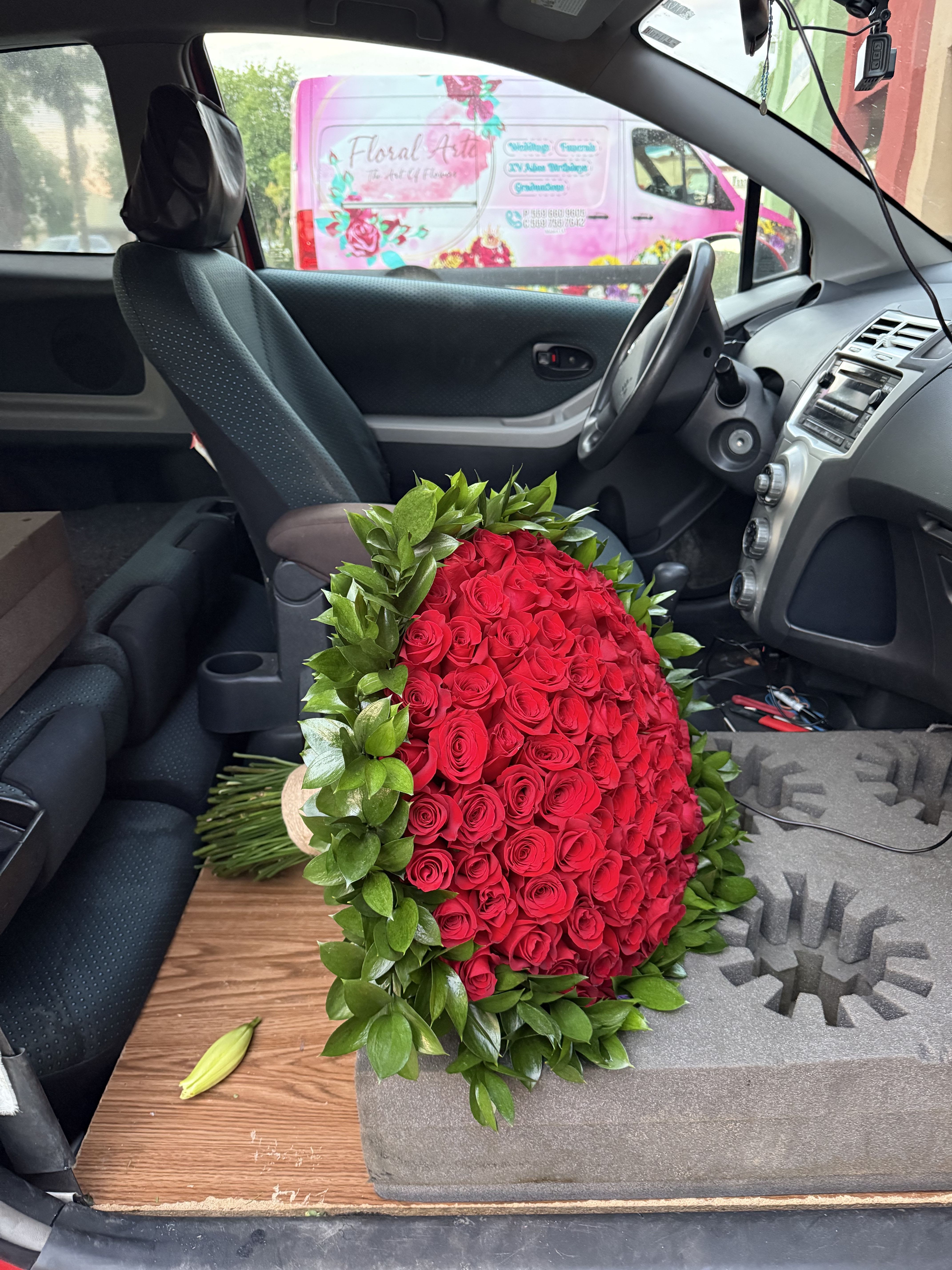 Large red rose bouquet with green foliage in a car interior
