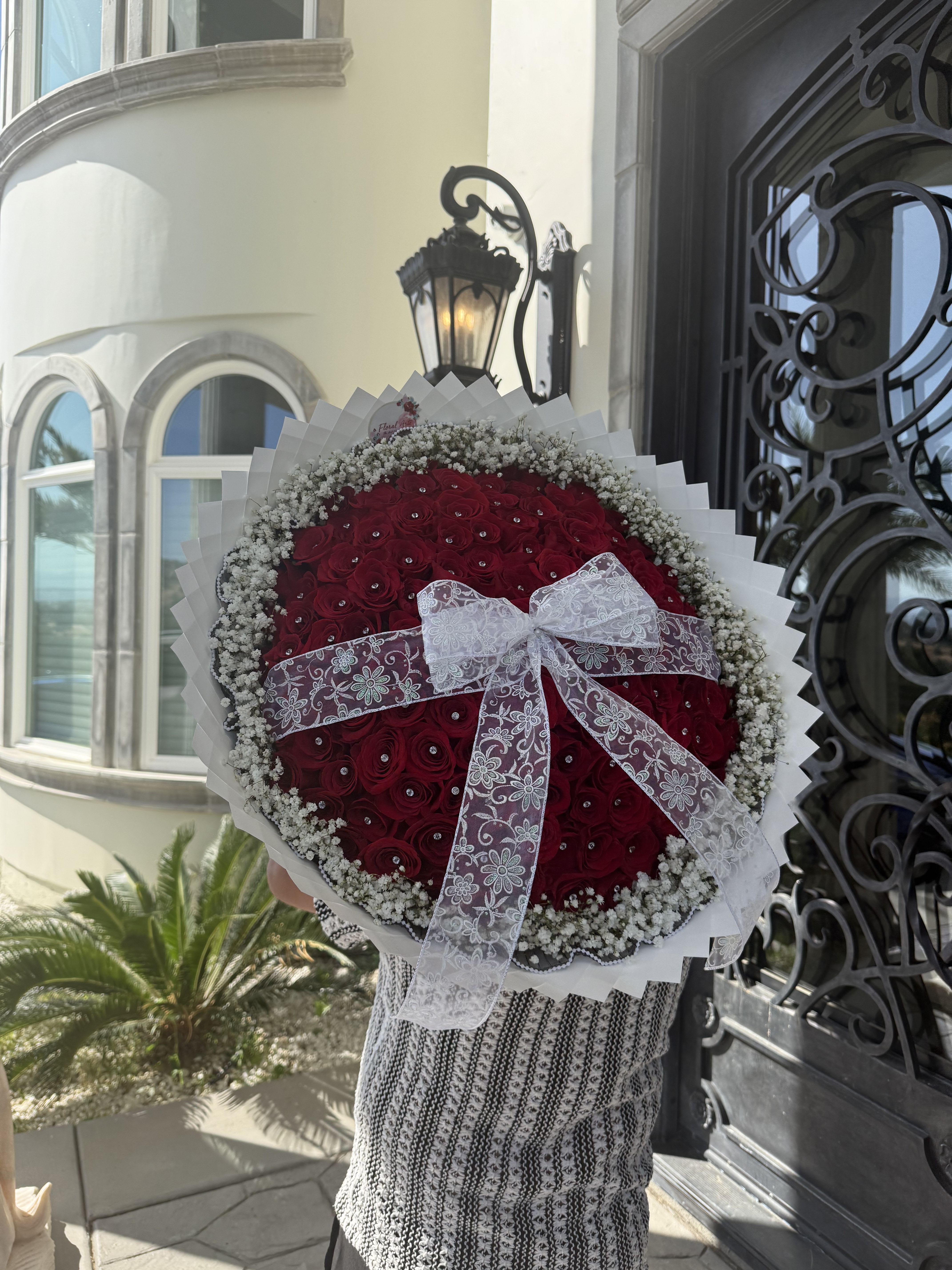 Large round bouquet of red roses with a white lace bow