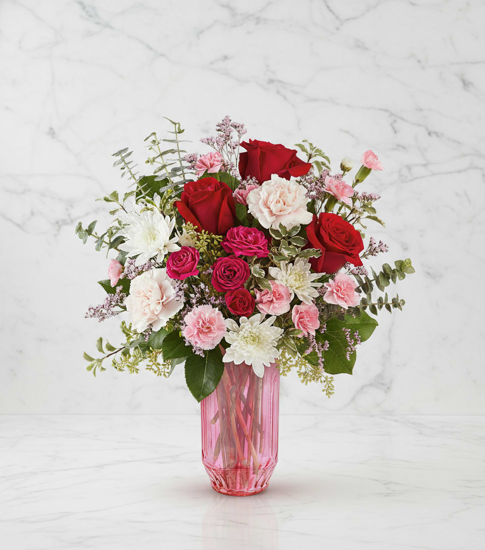Bouquet of red and pink flowers in a pink glass vase