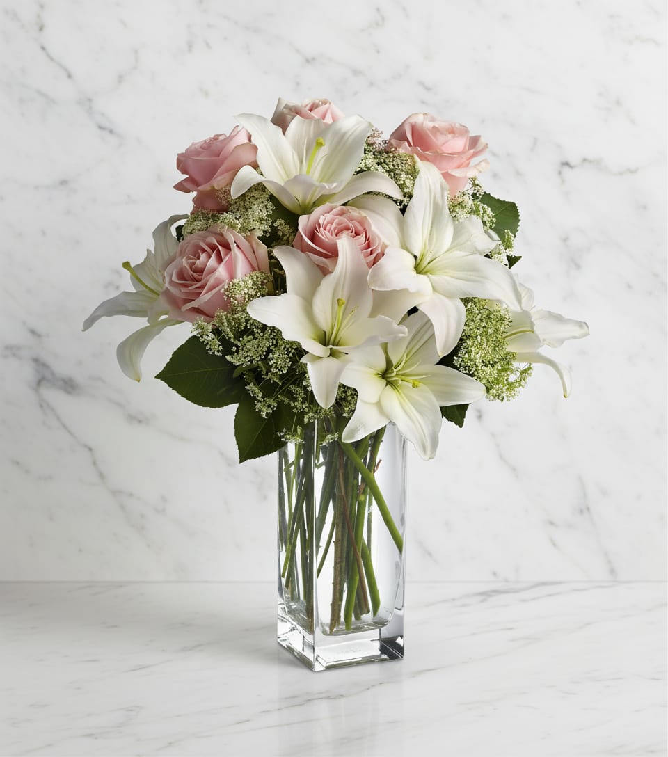 Pink roses and white lilies arranged in a clear glass vase
