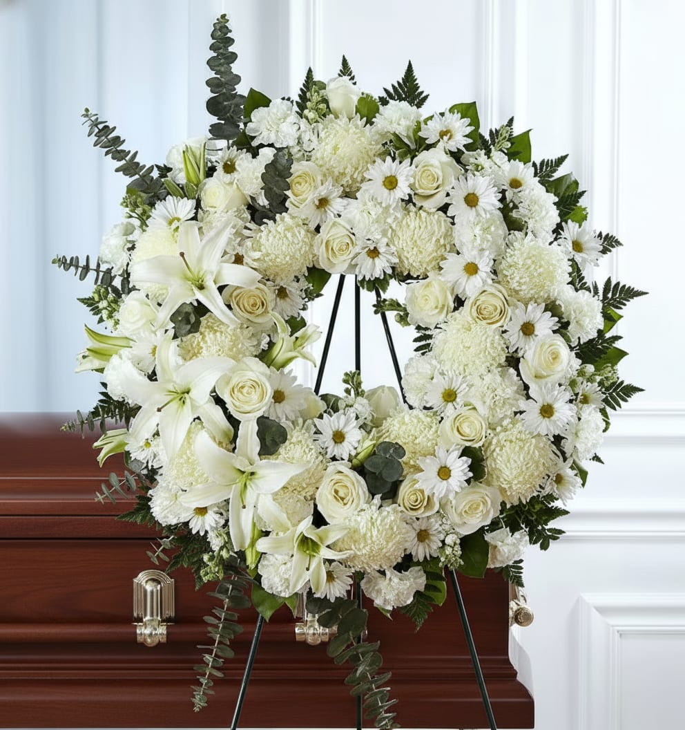 White floral wreath on a stand displayed over a casket