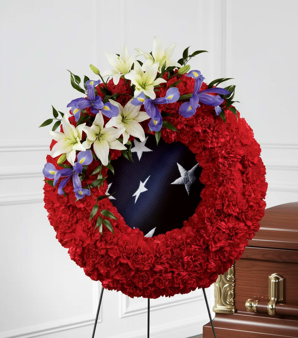 Red floral funeral wreath with white lilies and purple irises on a stand