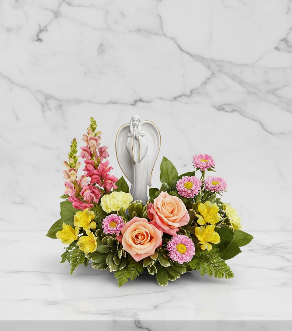 Angelic Bloom Bouquet - Radiating grace and serenity, our Angelic Bloom Bouquet surrounds a keepsake porcelain angel with peach roses, yellow blooms, and pink accents-offering a gentle reminder of peace, comfort, and lasting beauty.