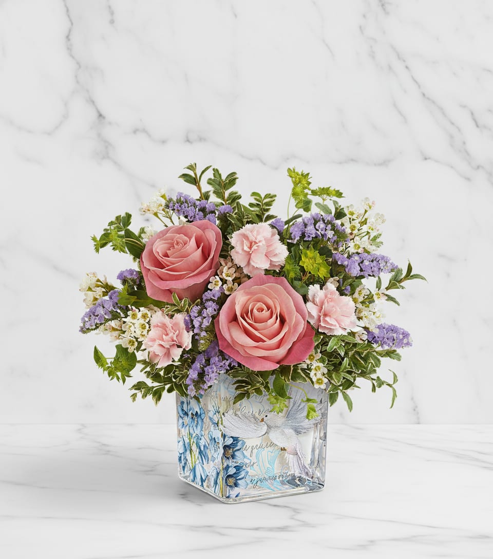 Whispers of Grace Bouquet - Softly serene, Our Whispers of Grace Bouquet blends pink roses and delicate pastel blooms in a glass cube adorned with peaceful doves and blossoms-a heartfelt reminder of love, hope, and gentle beauty.