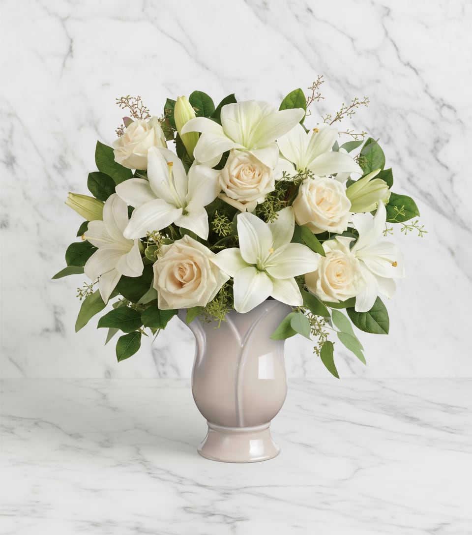 White lilies and cream roses arranged in a beige vase