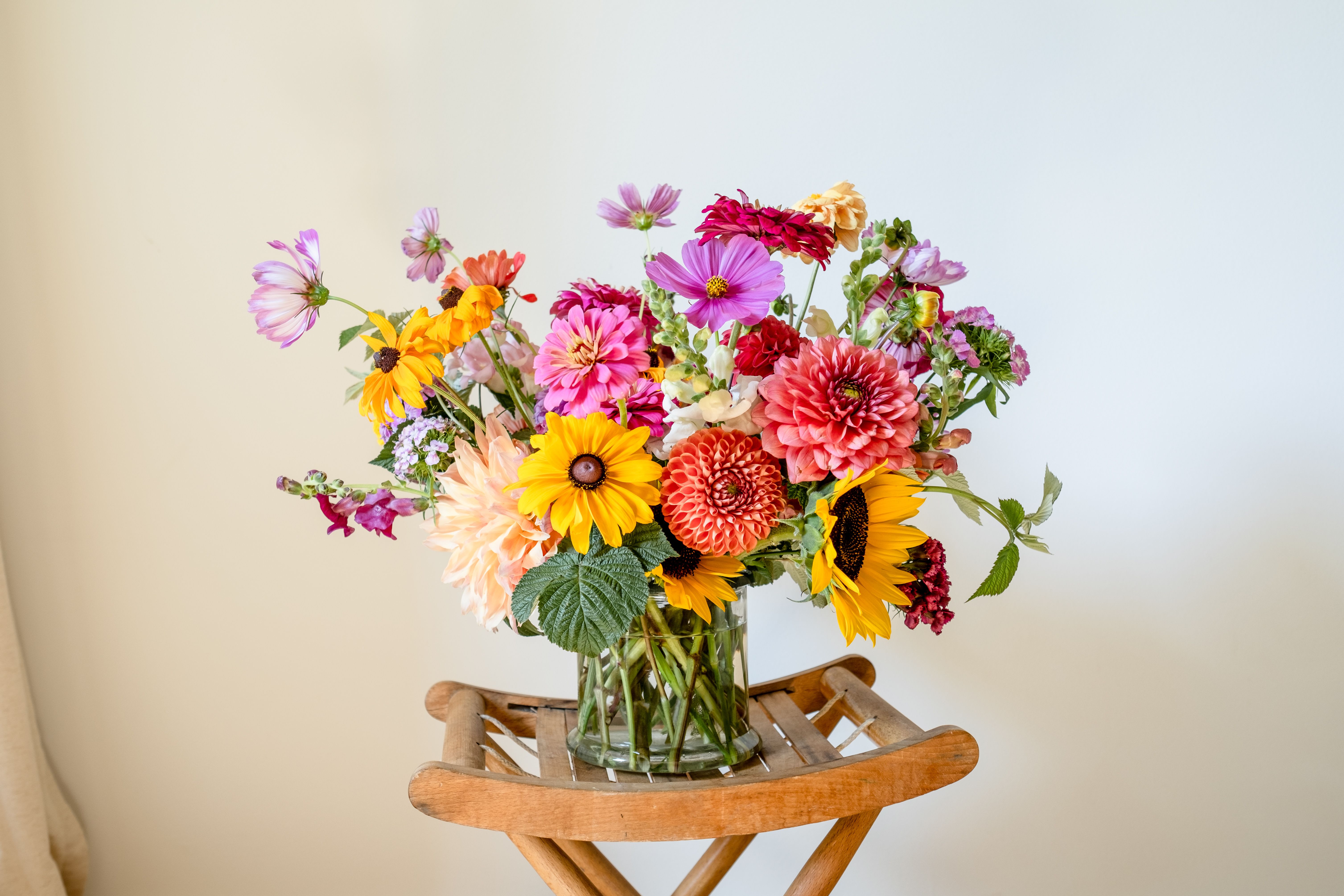 Colorful mixed bouquet in a clear glass vase on a wooden stand