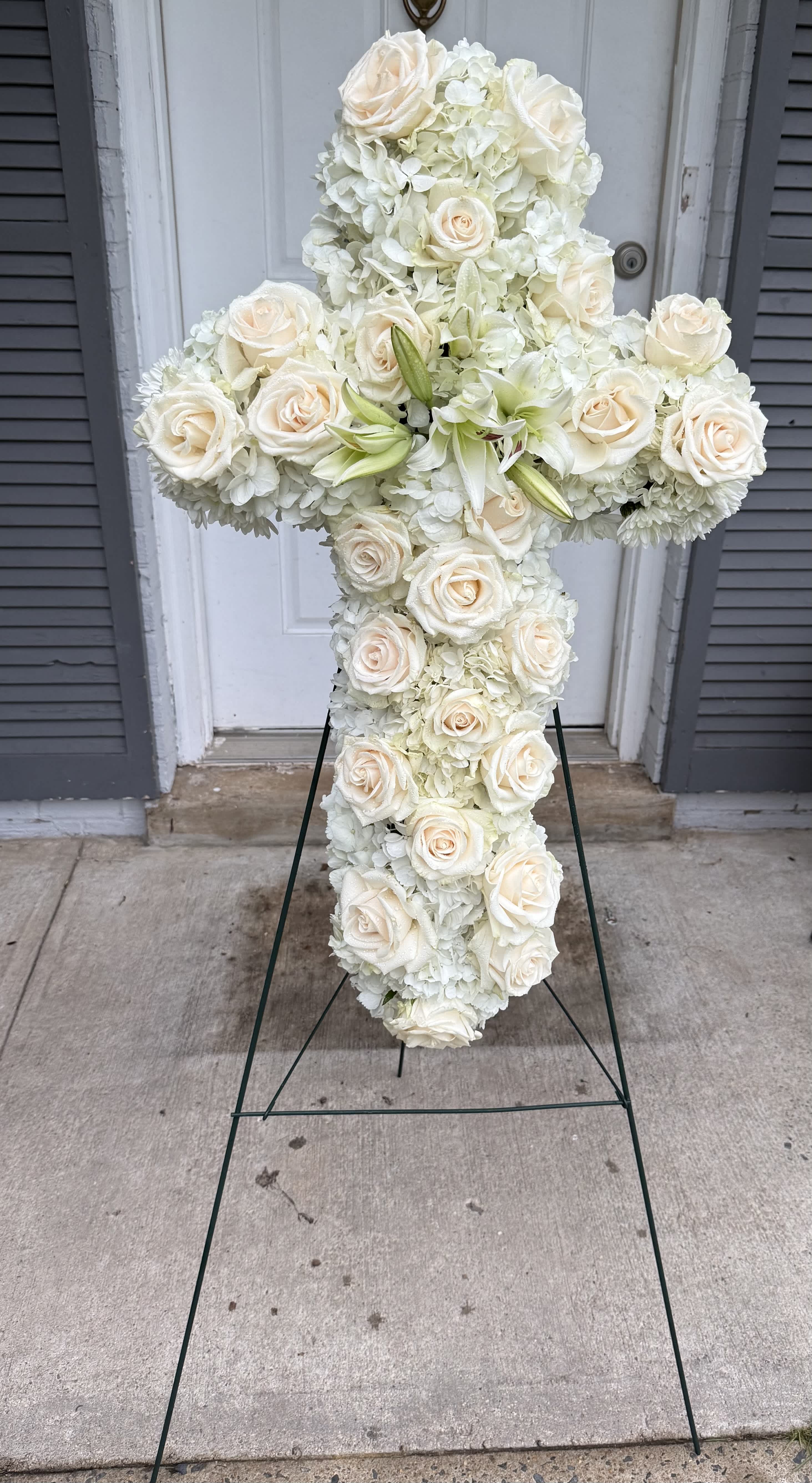 Faith Cross - An all white tribute, this white cross funeral spray is pure and tranquil. Featuring a variety of white flowers, this elegant easel compliments the beauty of life. 