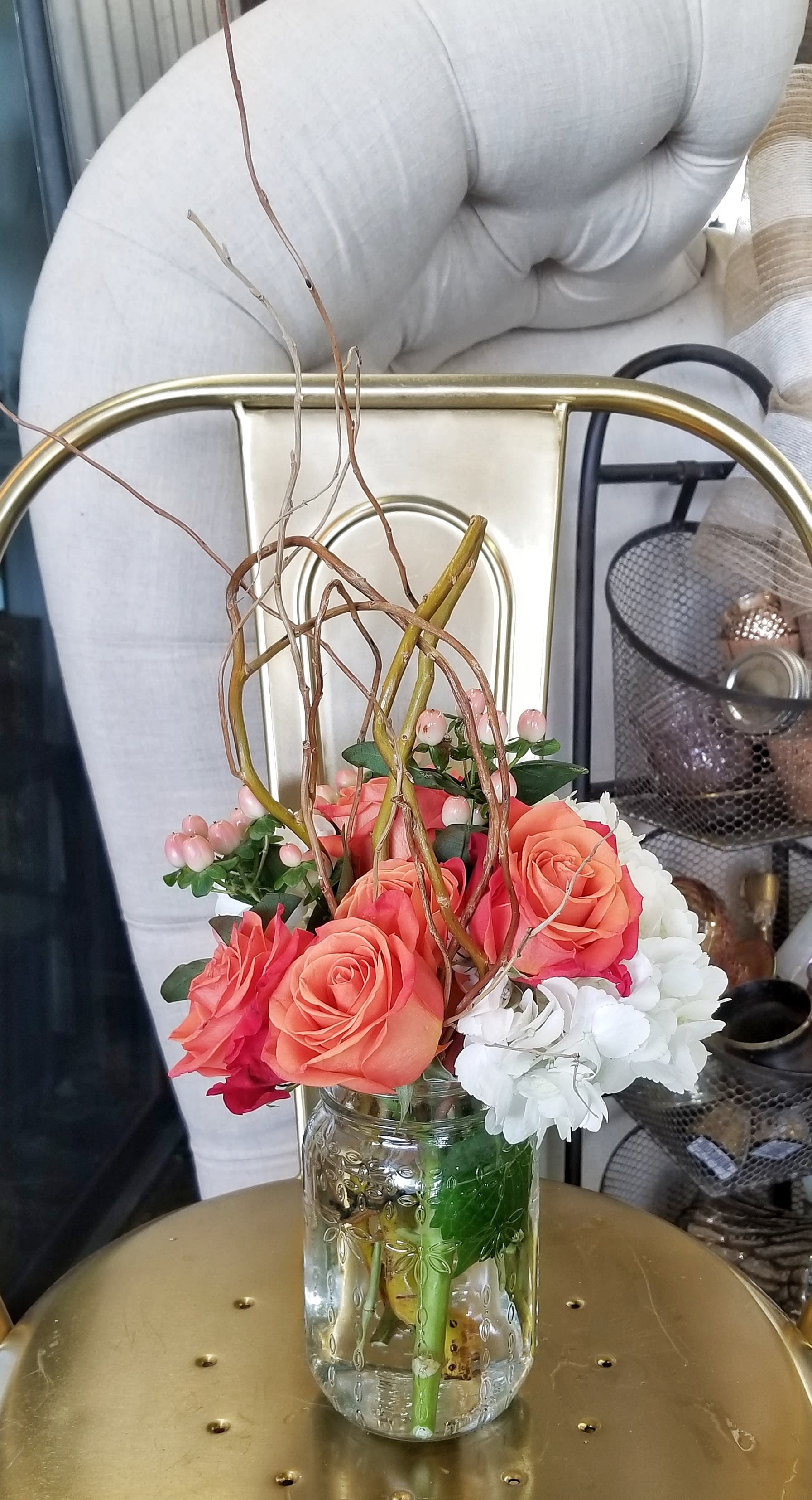 Coral roses and white flowers arranged in a clear glass jar