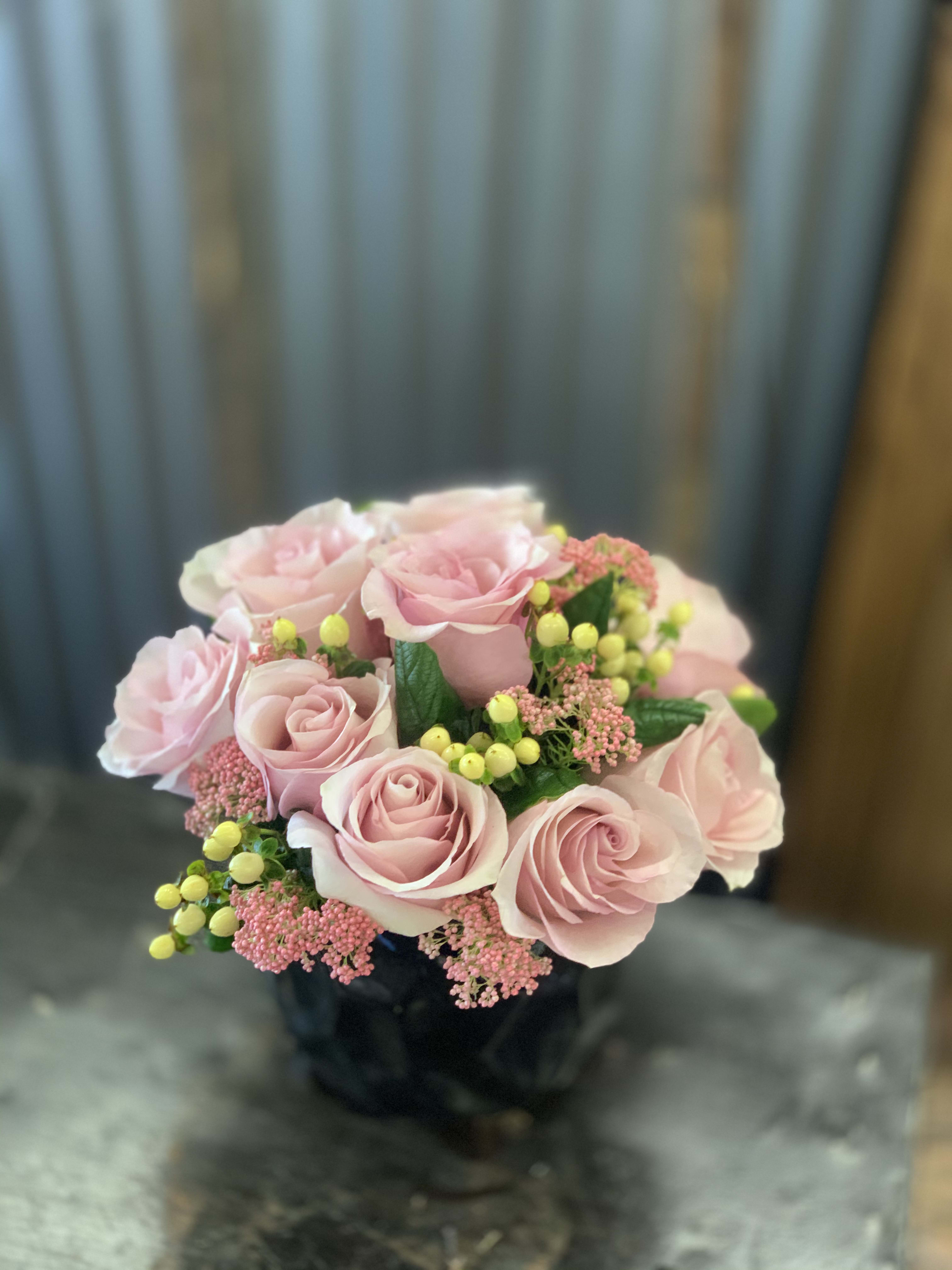 Pink rose bouquet with yellow berry accents in a dark vase
