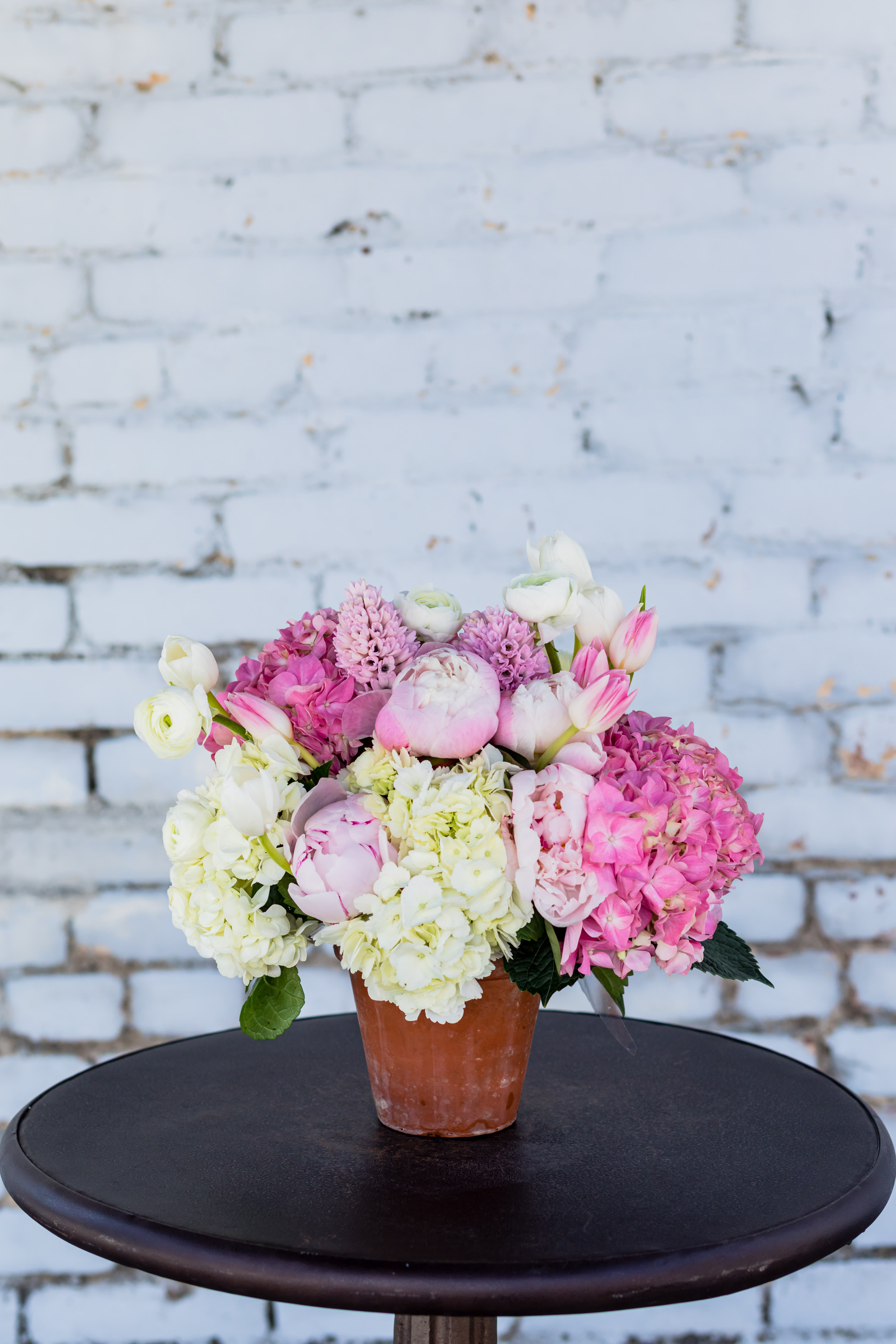 Pink and white flowers arranged in a terracotta pot