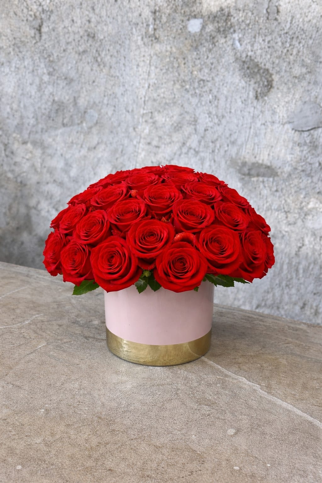 Round bouquet of red roses in a pink and gold box