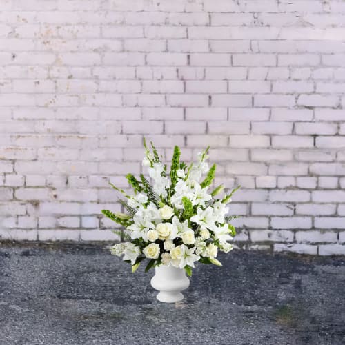 White floral arrangement in a white pedestal vase