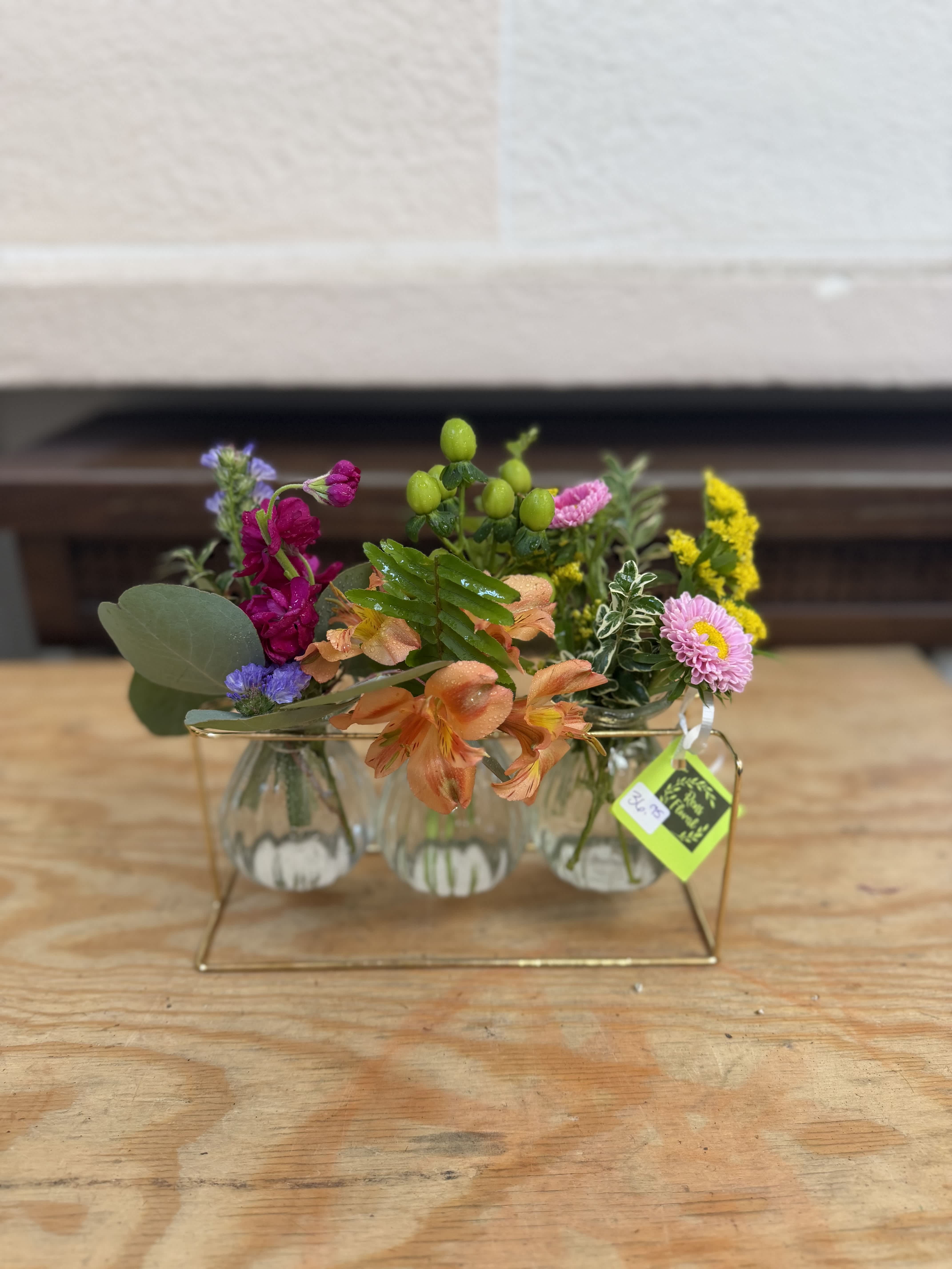 Small mixed flower arrangement in clear glass vases on a gold stand