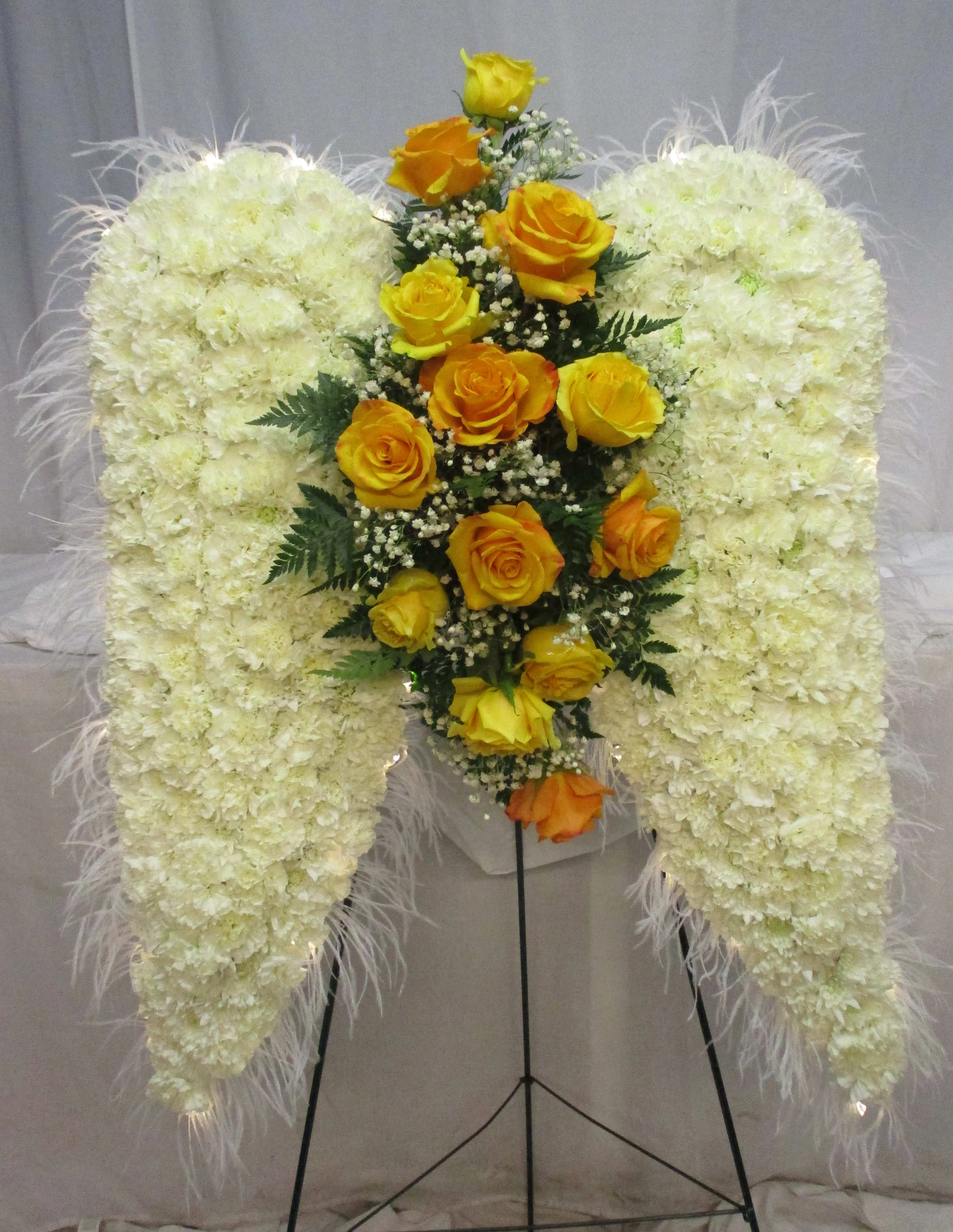 White floral standing spray with yellow roses on a metal easel