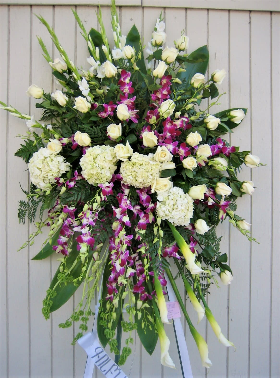 Large standing sympathy spray with white roses, orchids, and calla lilies