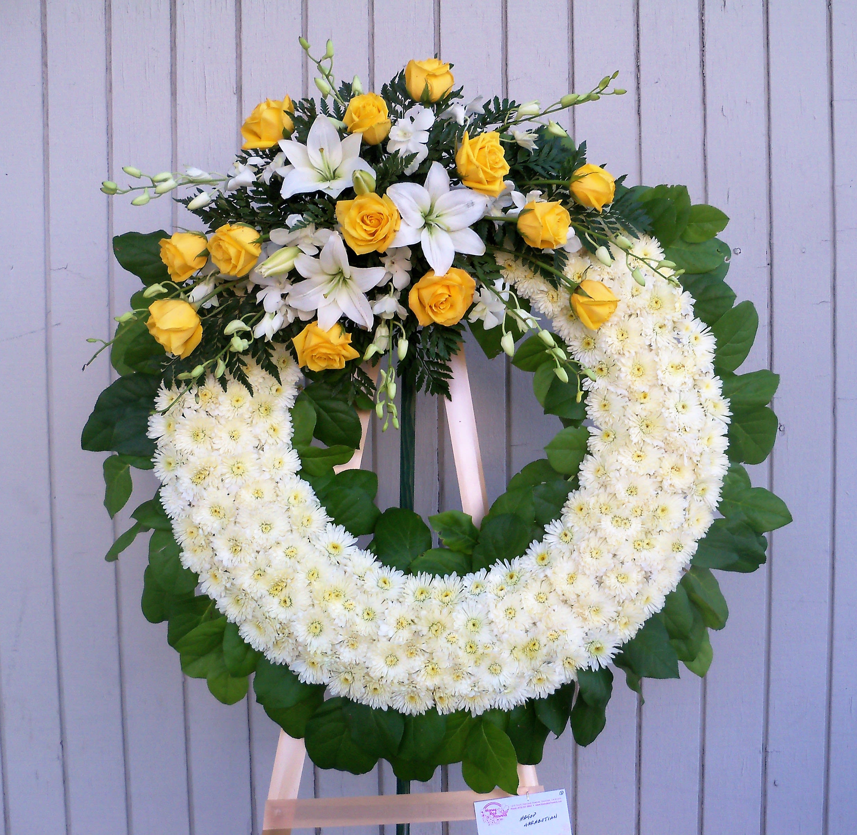 Yellow roses and white lilies arranged in a large floral wreath