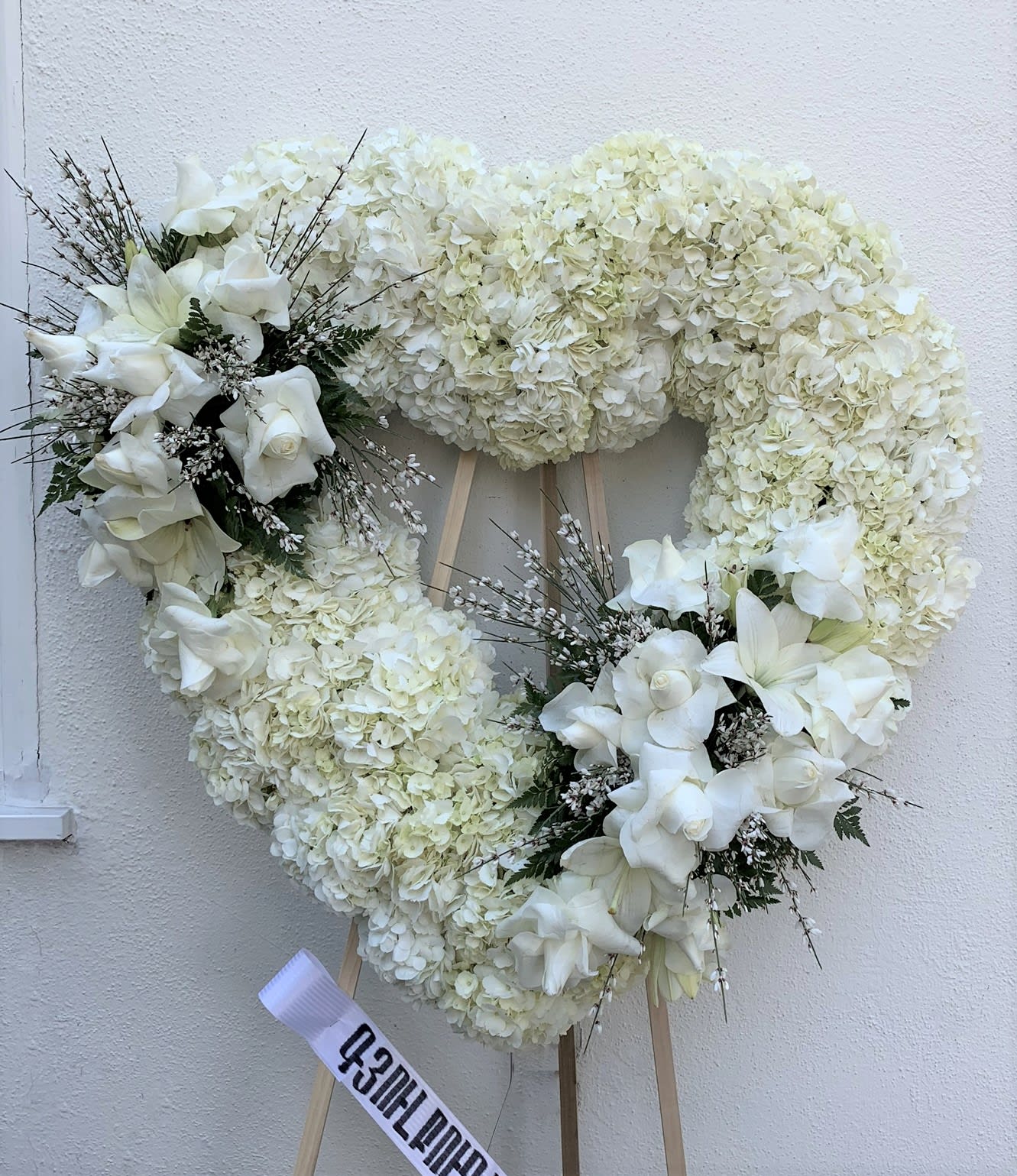 White floral heart wreath on an easel with ribbon