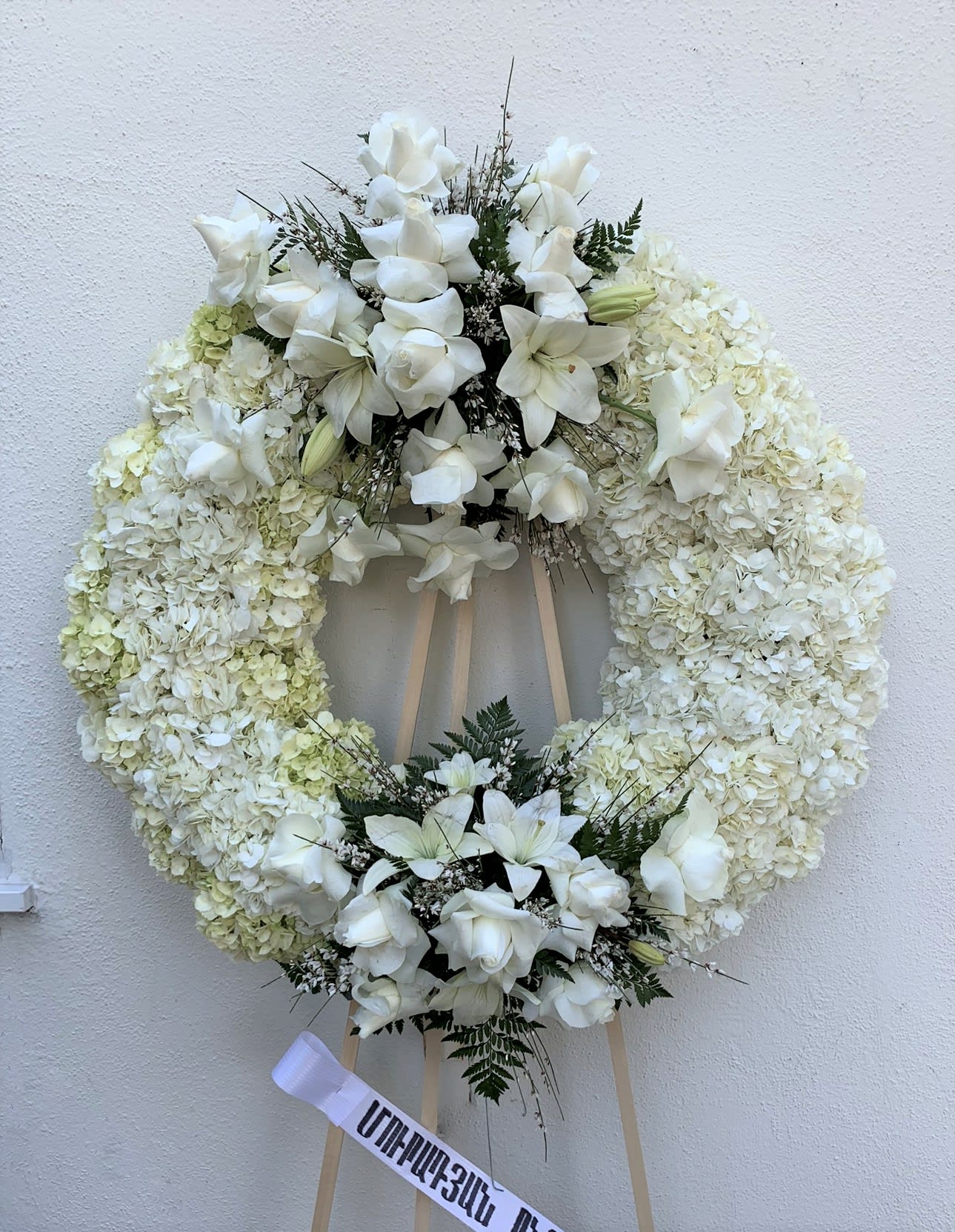 White floral funeral wreath on a wooden easel