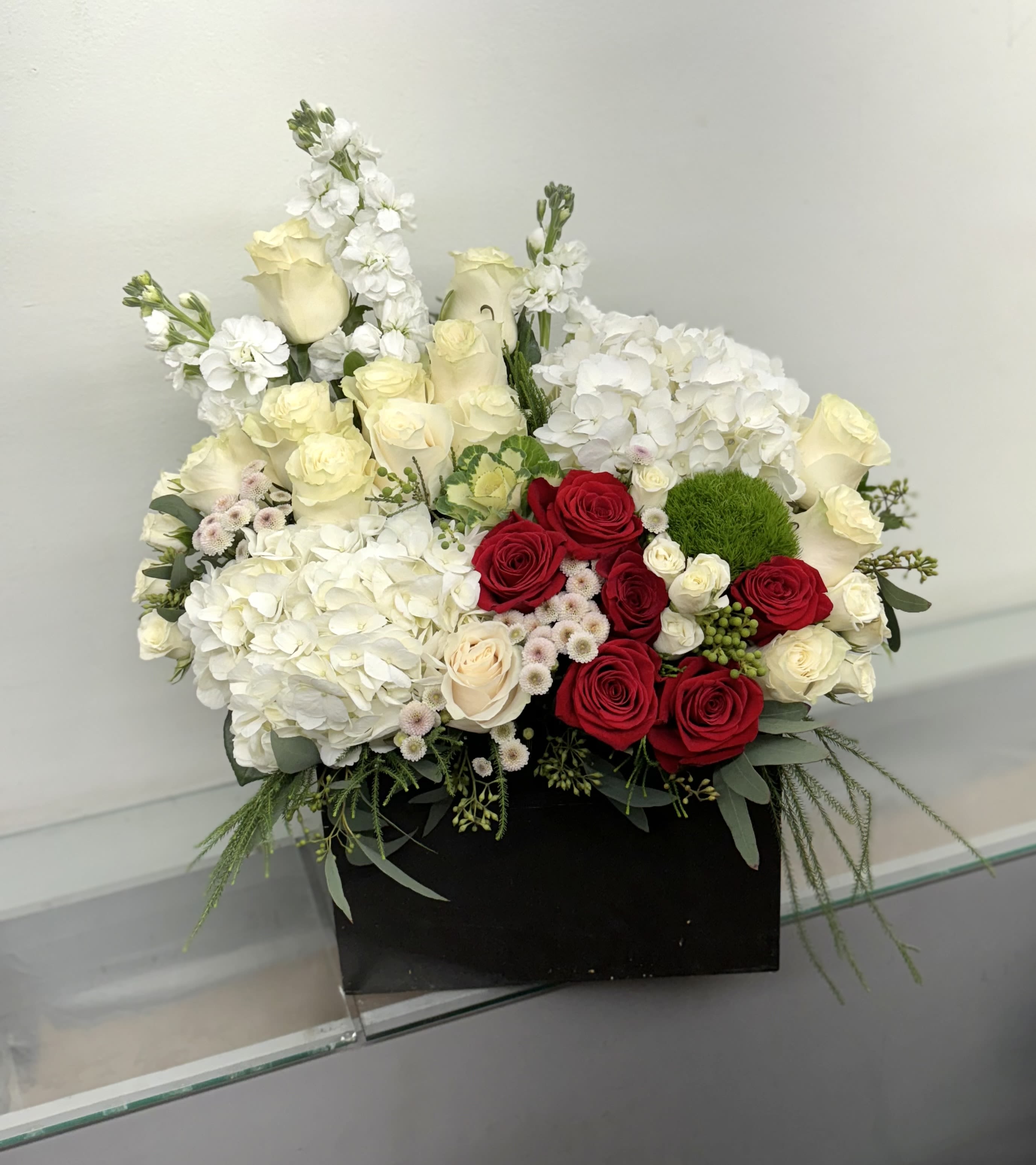 Mixed bouquet of red and white roses with white hydrangeas in a black box