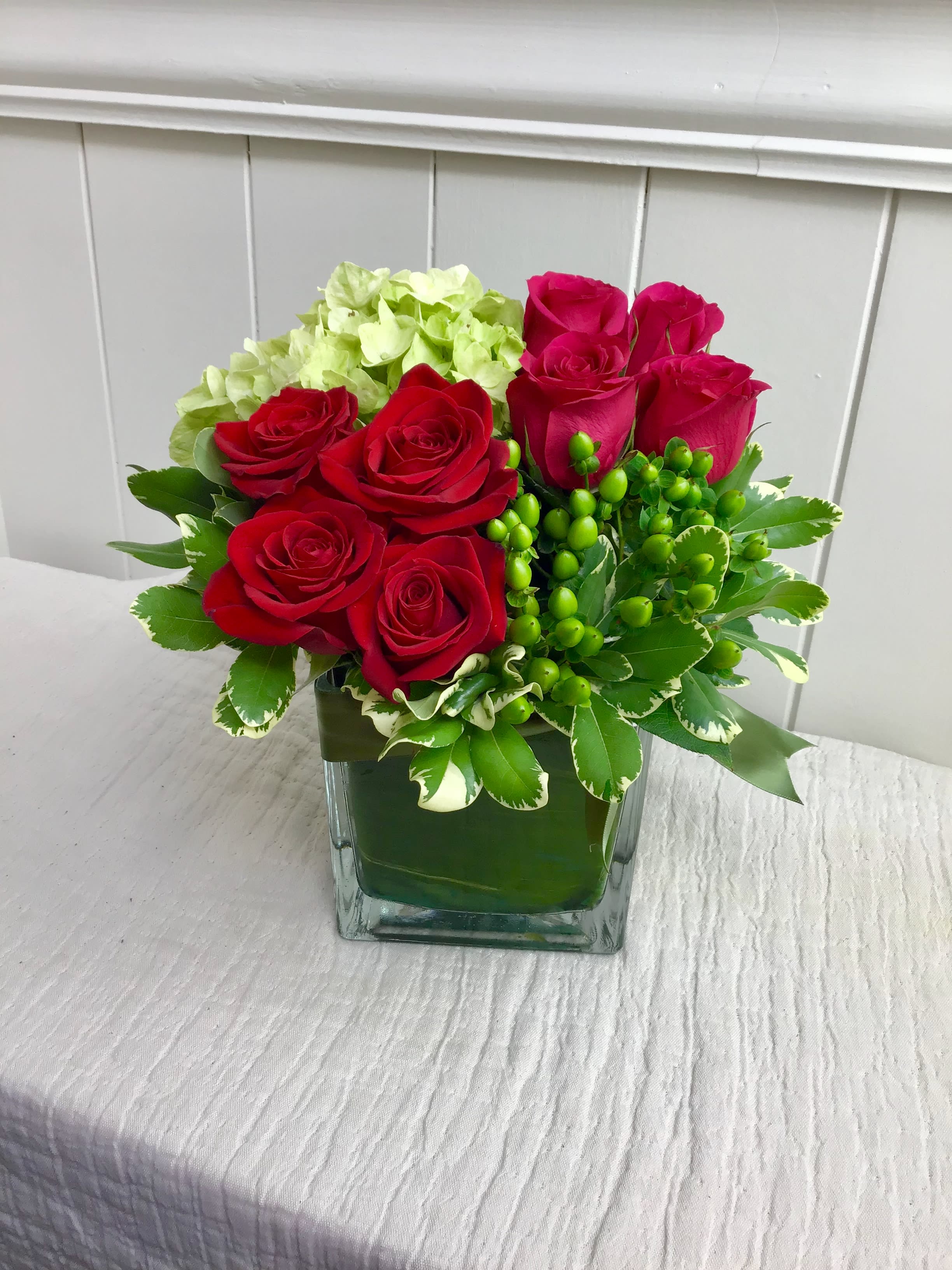 Red roses and green hydrangea in a square glass vase