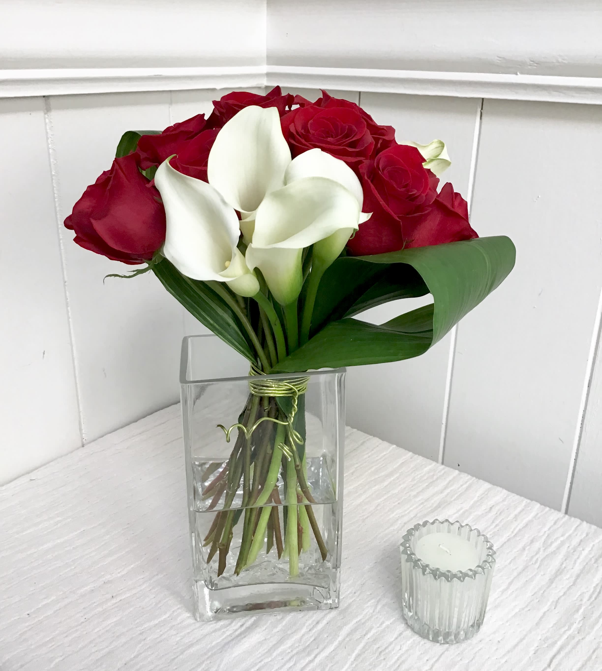 Red roses and white calla lilies in a clear glass vase