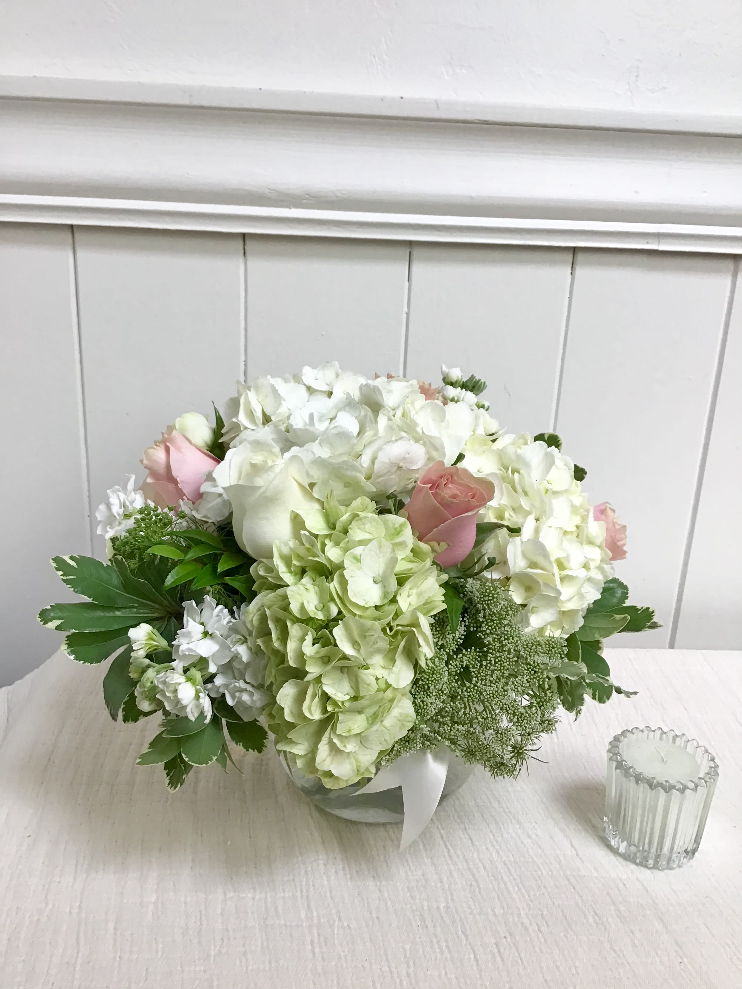 White and pale pink bouquet with hydrangeas and roses in a low container
