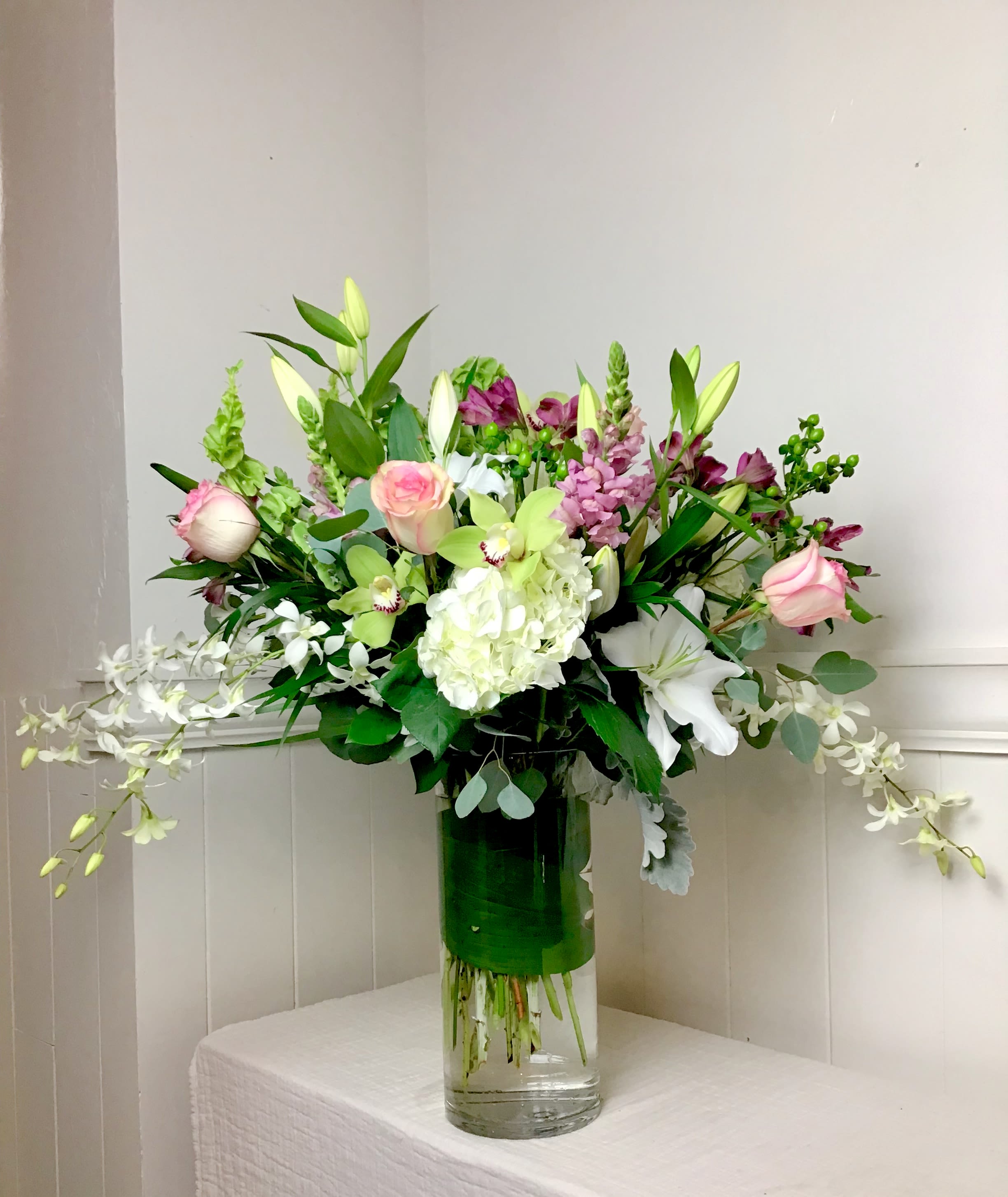 Mixed bouquet in a clear glass vase with pink, white, and green flowers