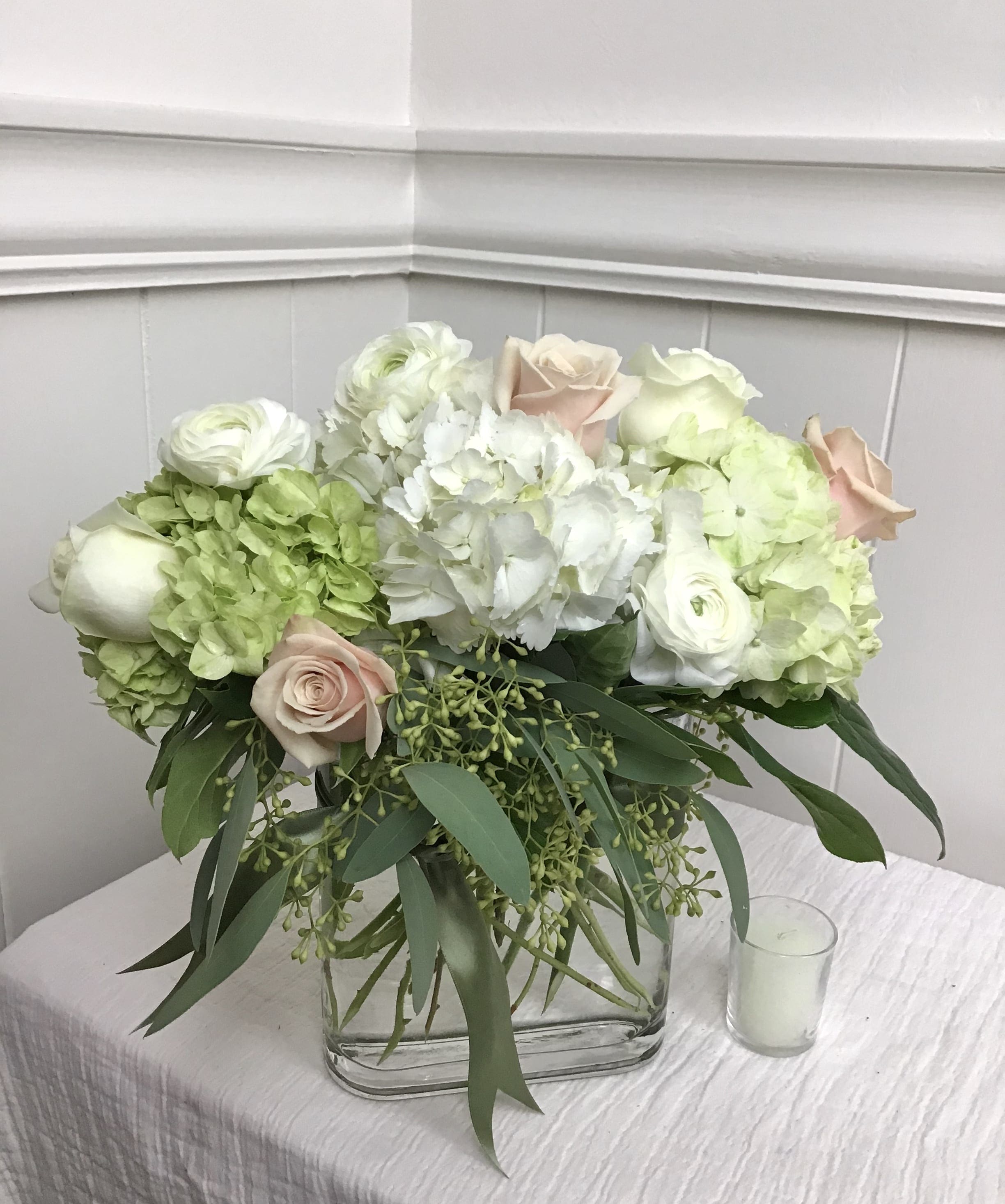 White and blush floral arrangement in a clear rectangular vase